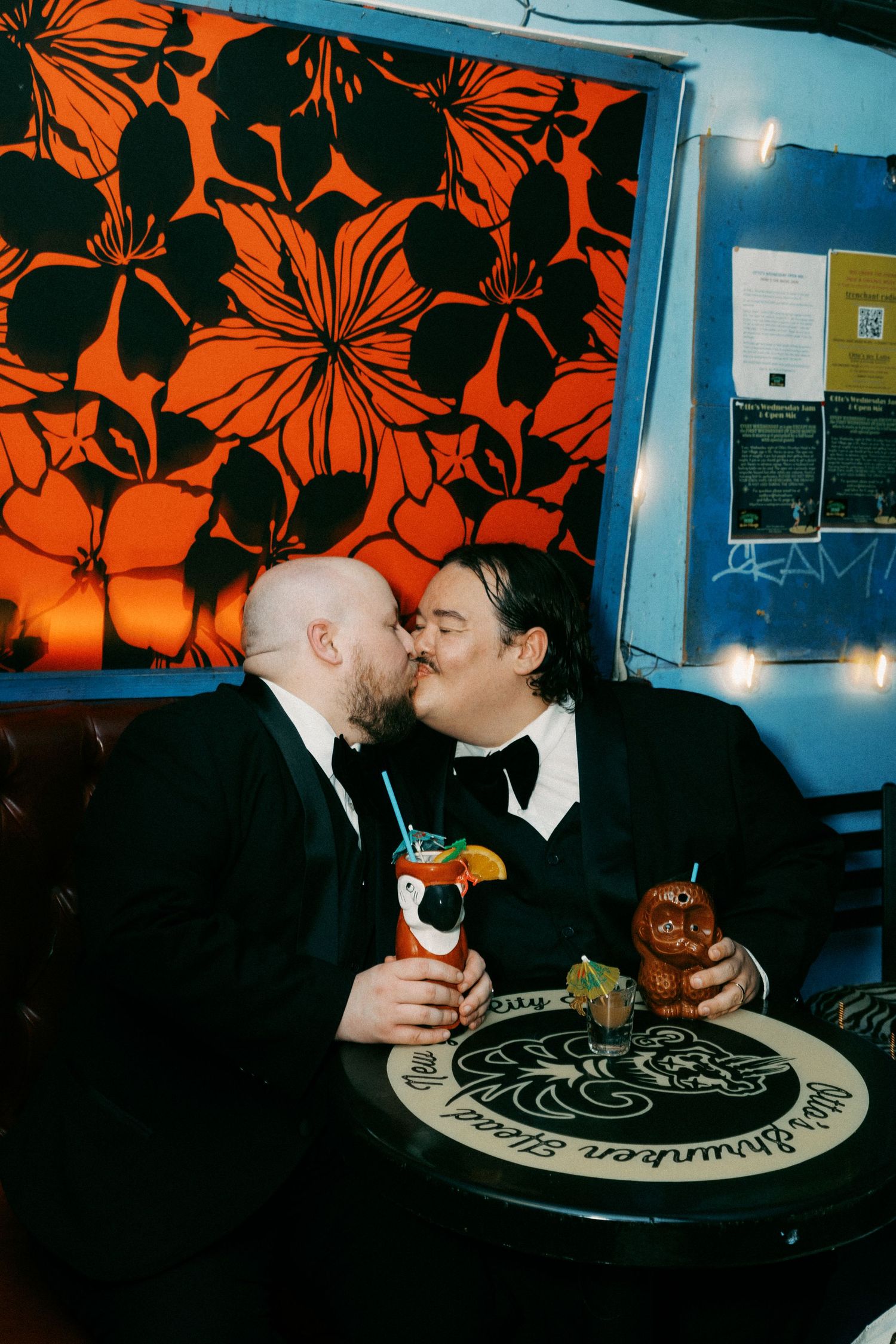 Two people sharing a meal at a restaurant with vibrant orange floral wallpaper.