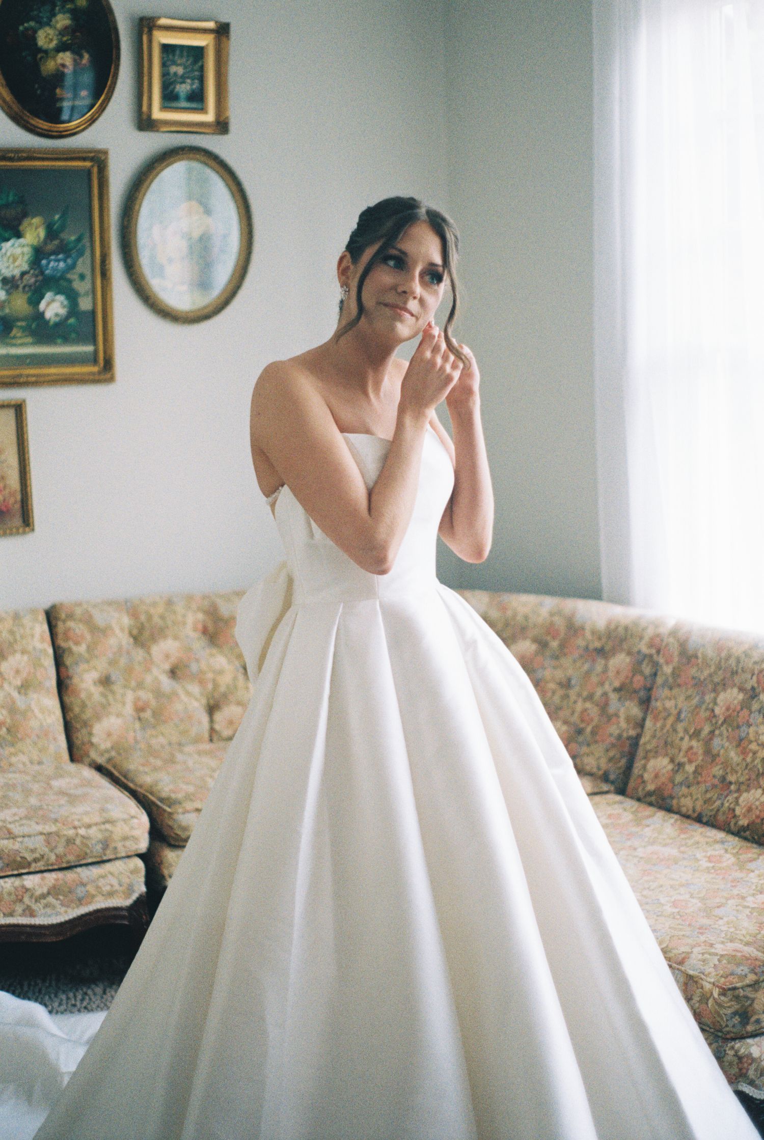 A wedding dress reveal moment in an elegantly decorated living room with floral furniture.
