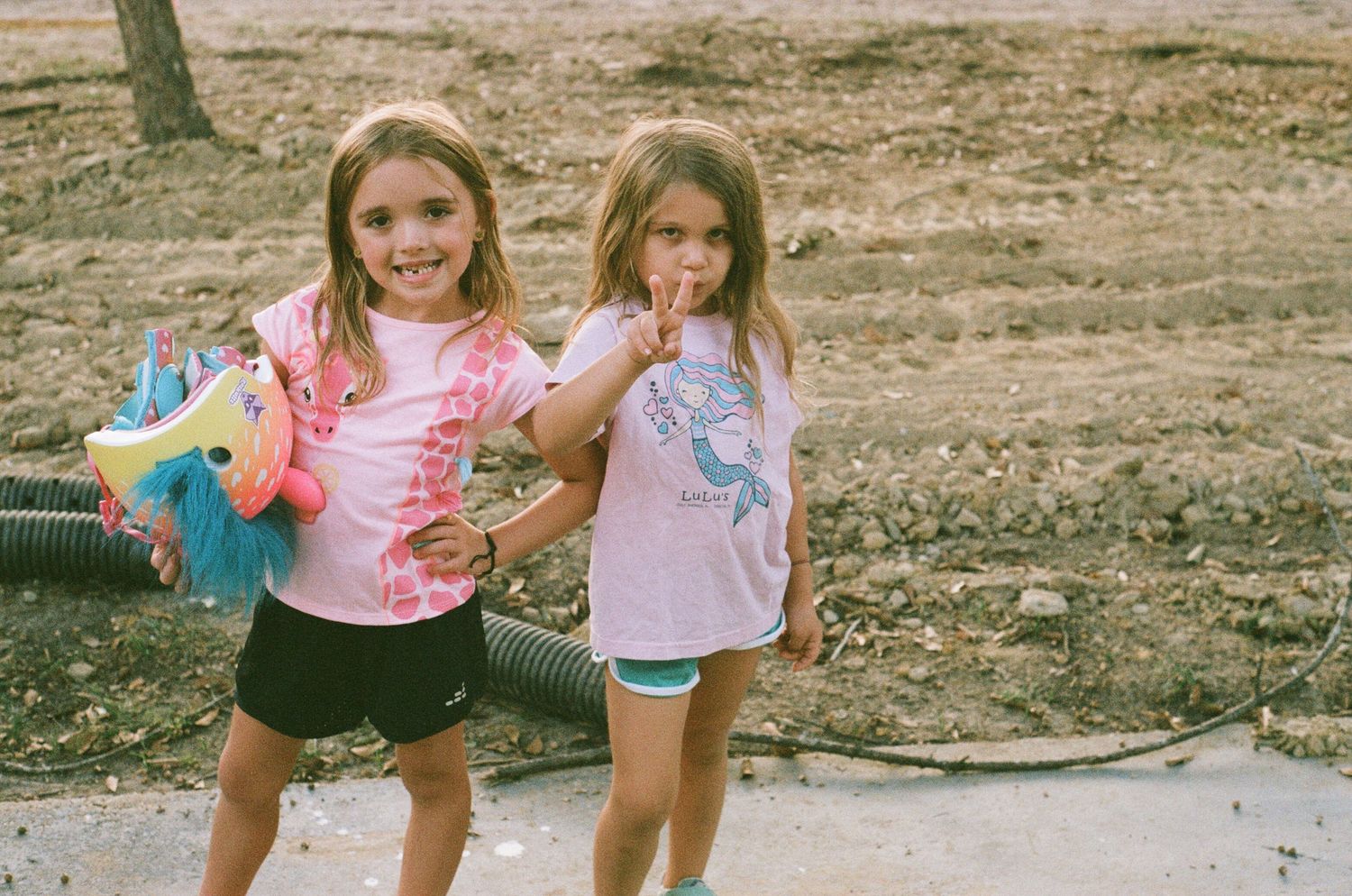 Children playing outdoors in colorful clothing on a sunny day.