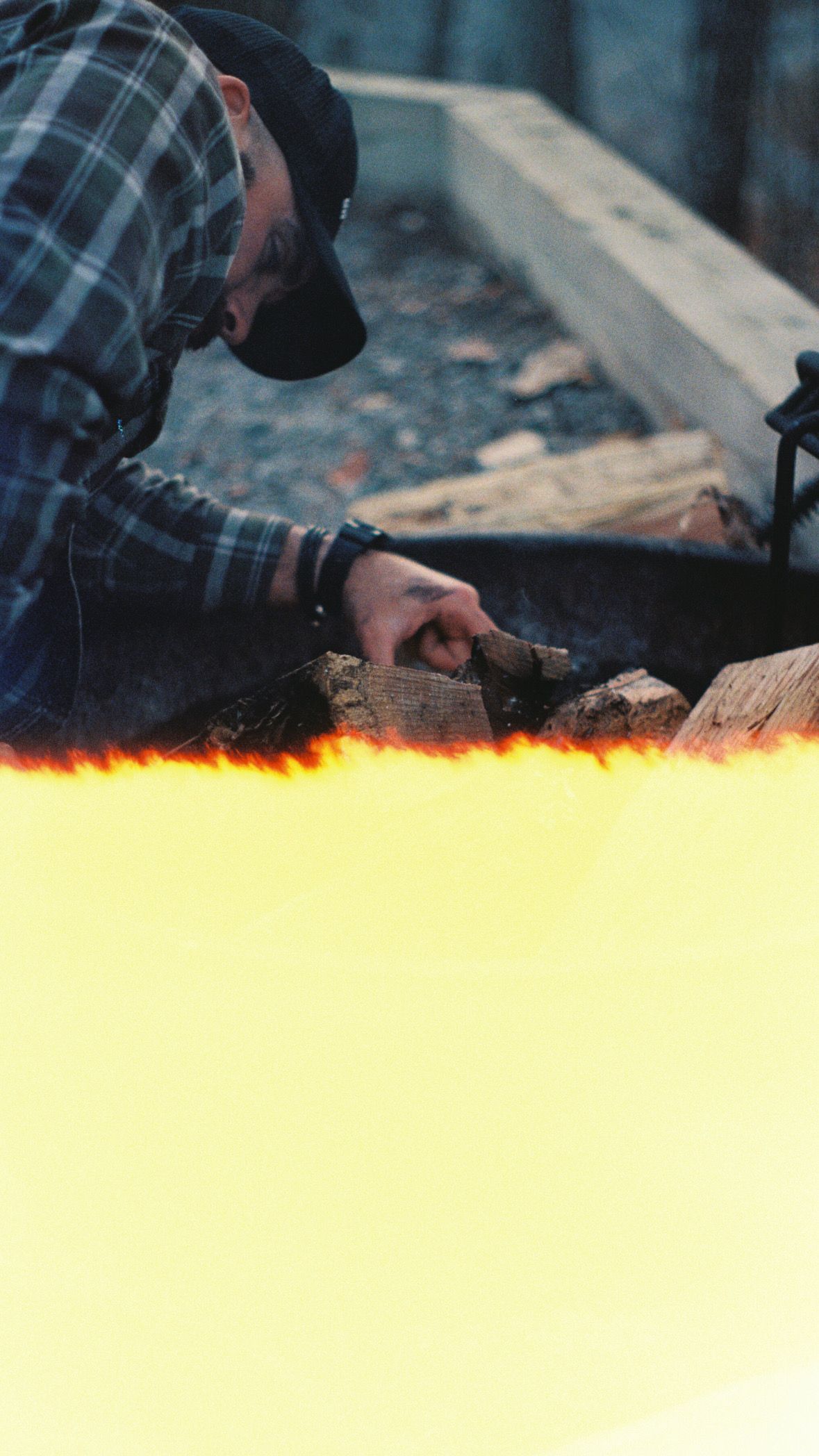 Close-up of hands tending to a campfire with bright flames.