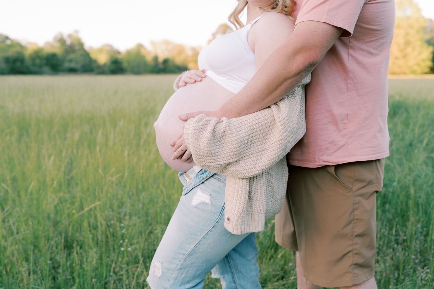 A tender moment captured in soft sunlight against a natural field backdrop.