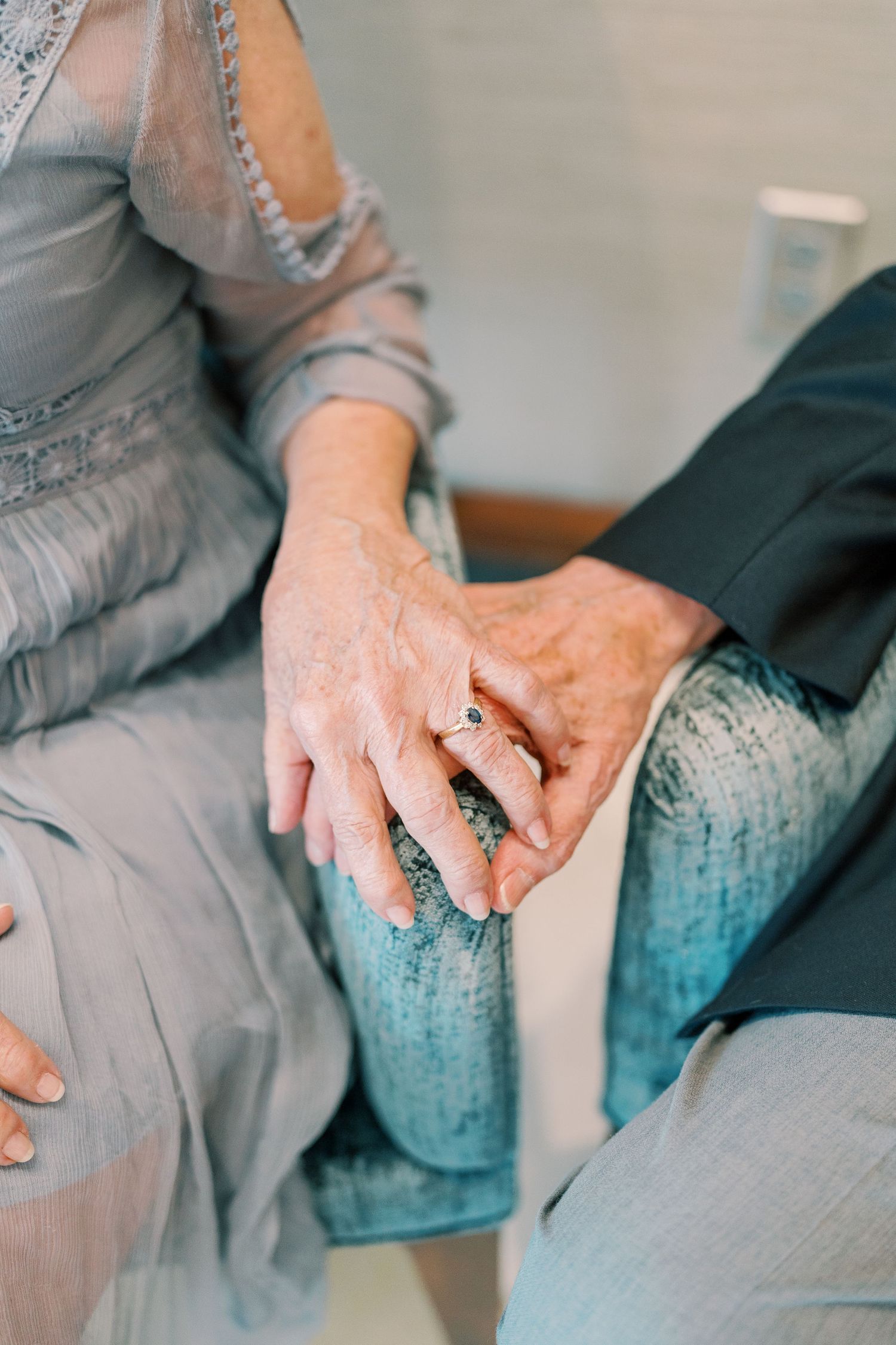 Close-up of hands resting on blue upholstered couch cushions.