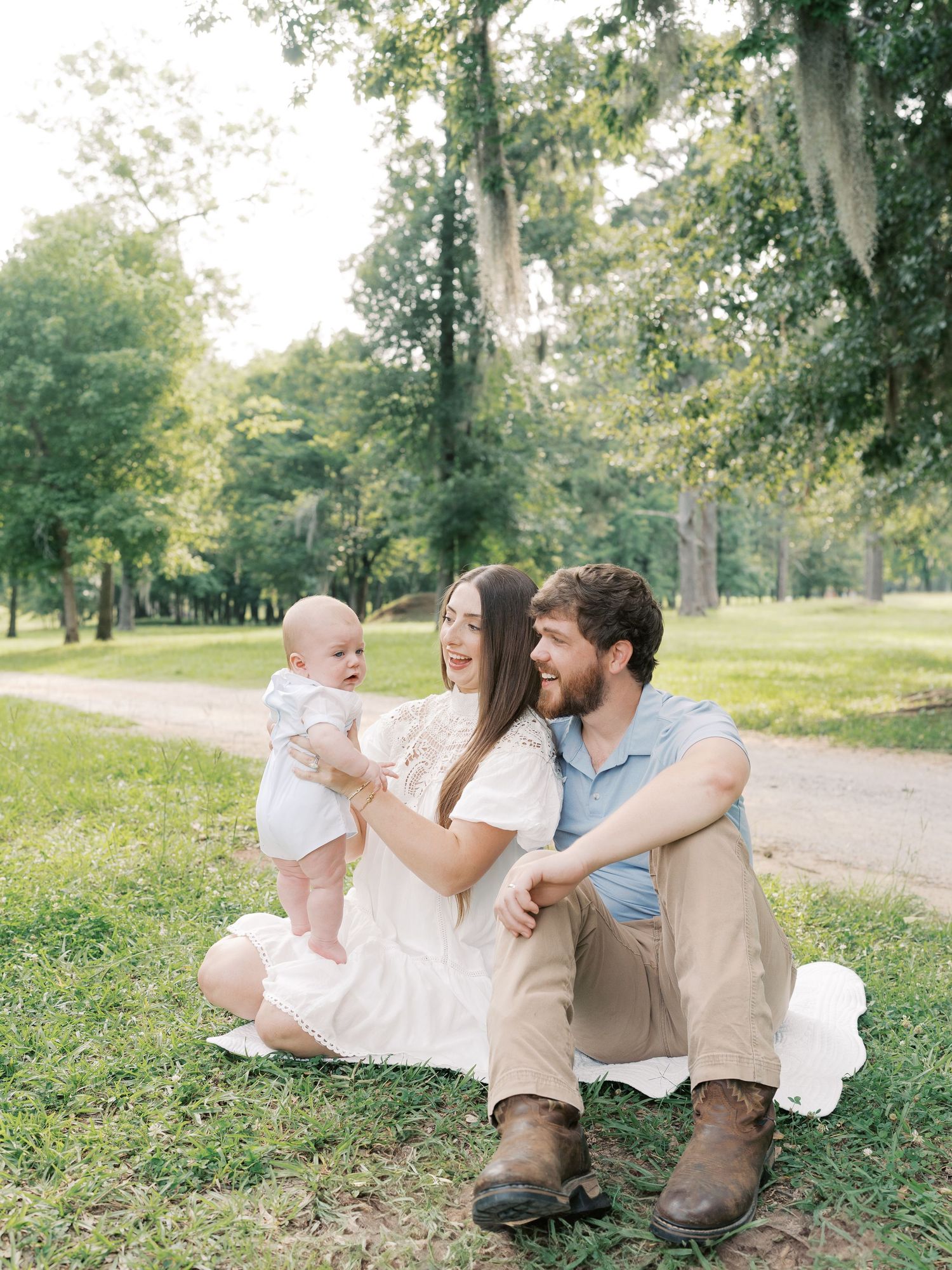 A family relaxes together on grassy ground during an outdoor photo session.