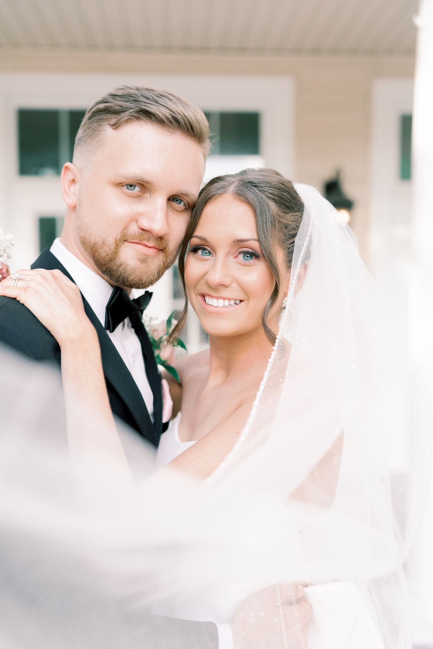 Soft, dreamy wedding portraits with a white veil creating romantic atmosphere.