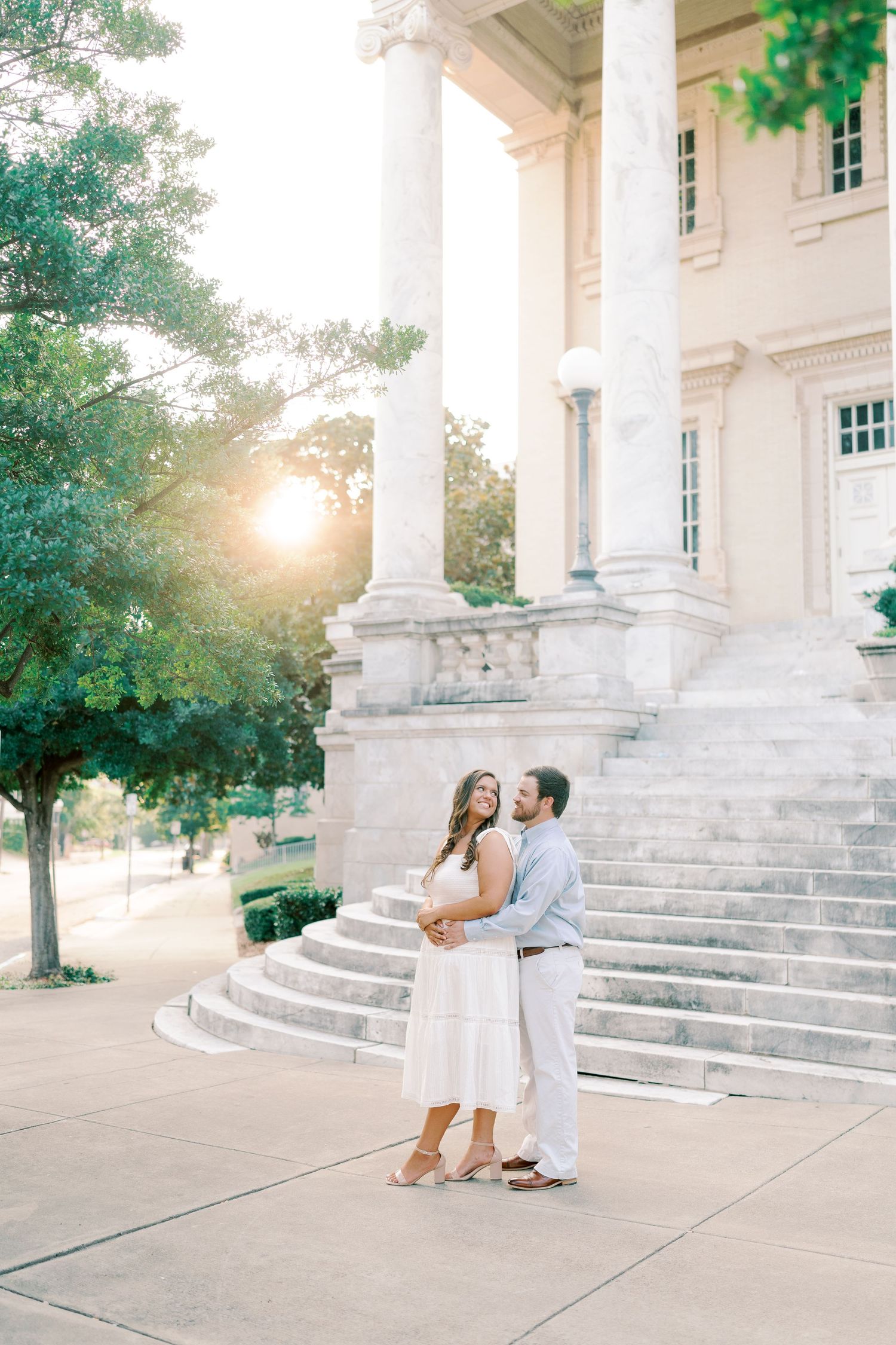 A couple shares tender moments on grand white marble steps during golden hour.