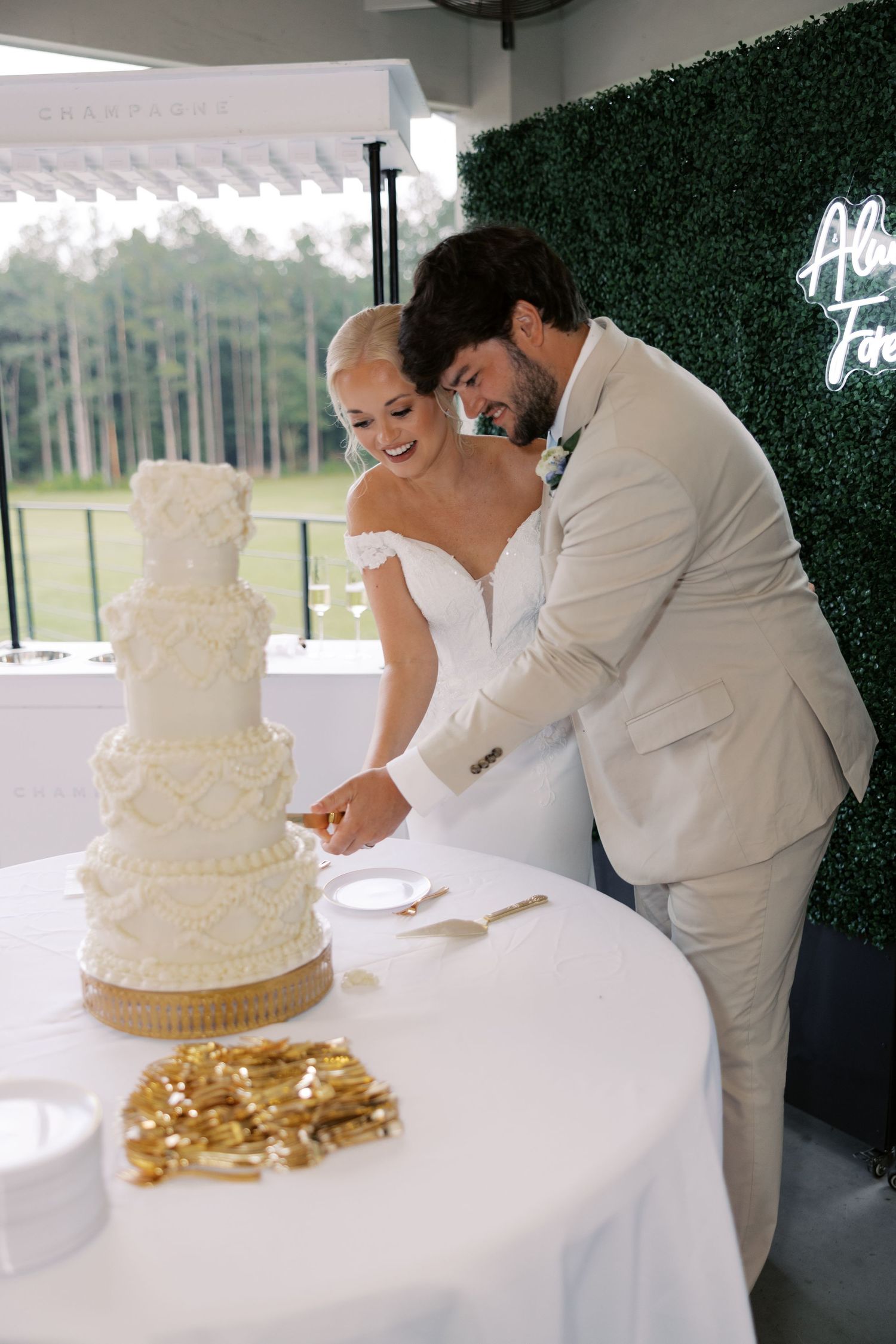 A couple cuts their elegant white wedding cake at their reception.