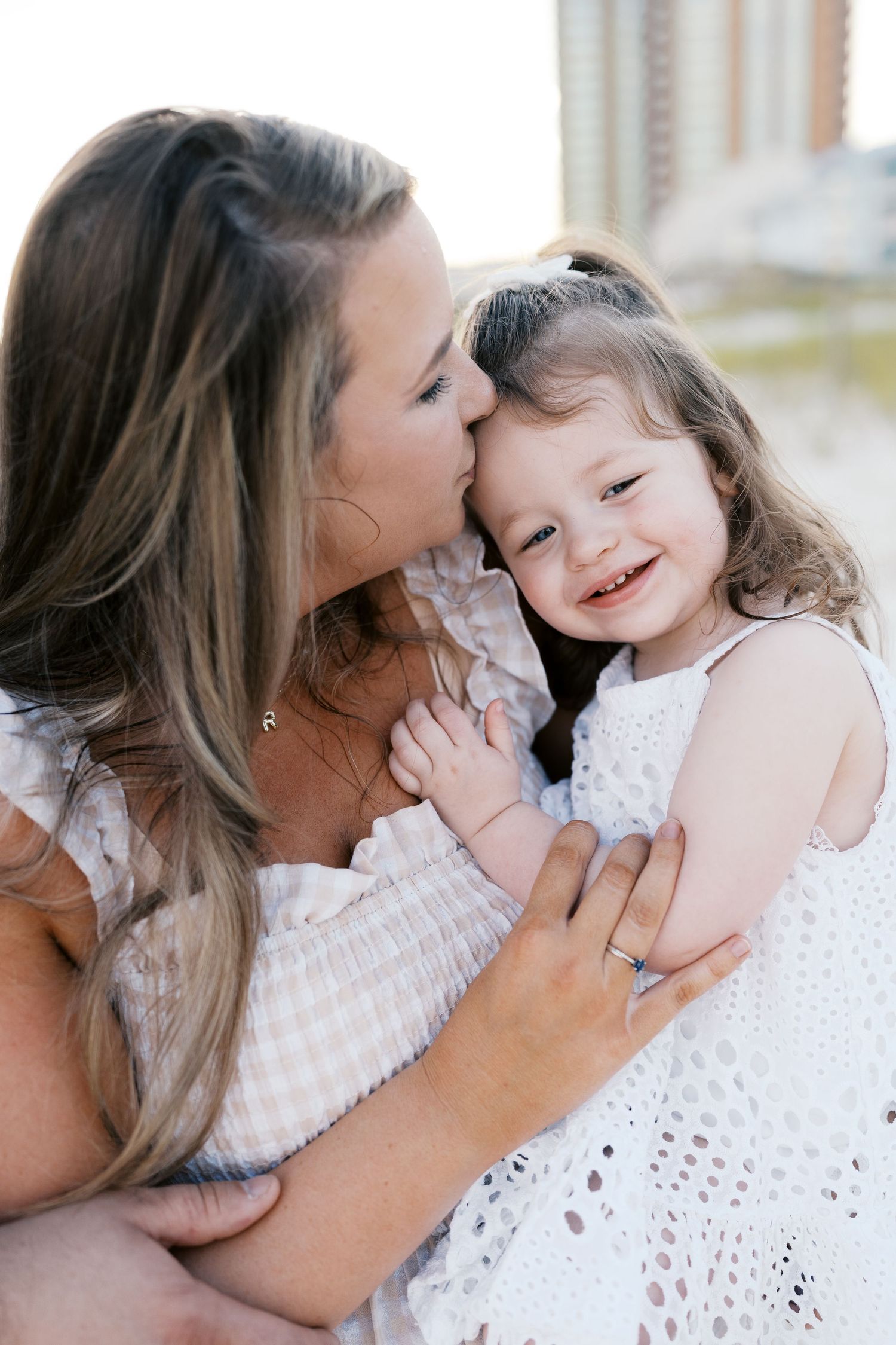 Intimate family moments captured in white dresses against a bright background.