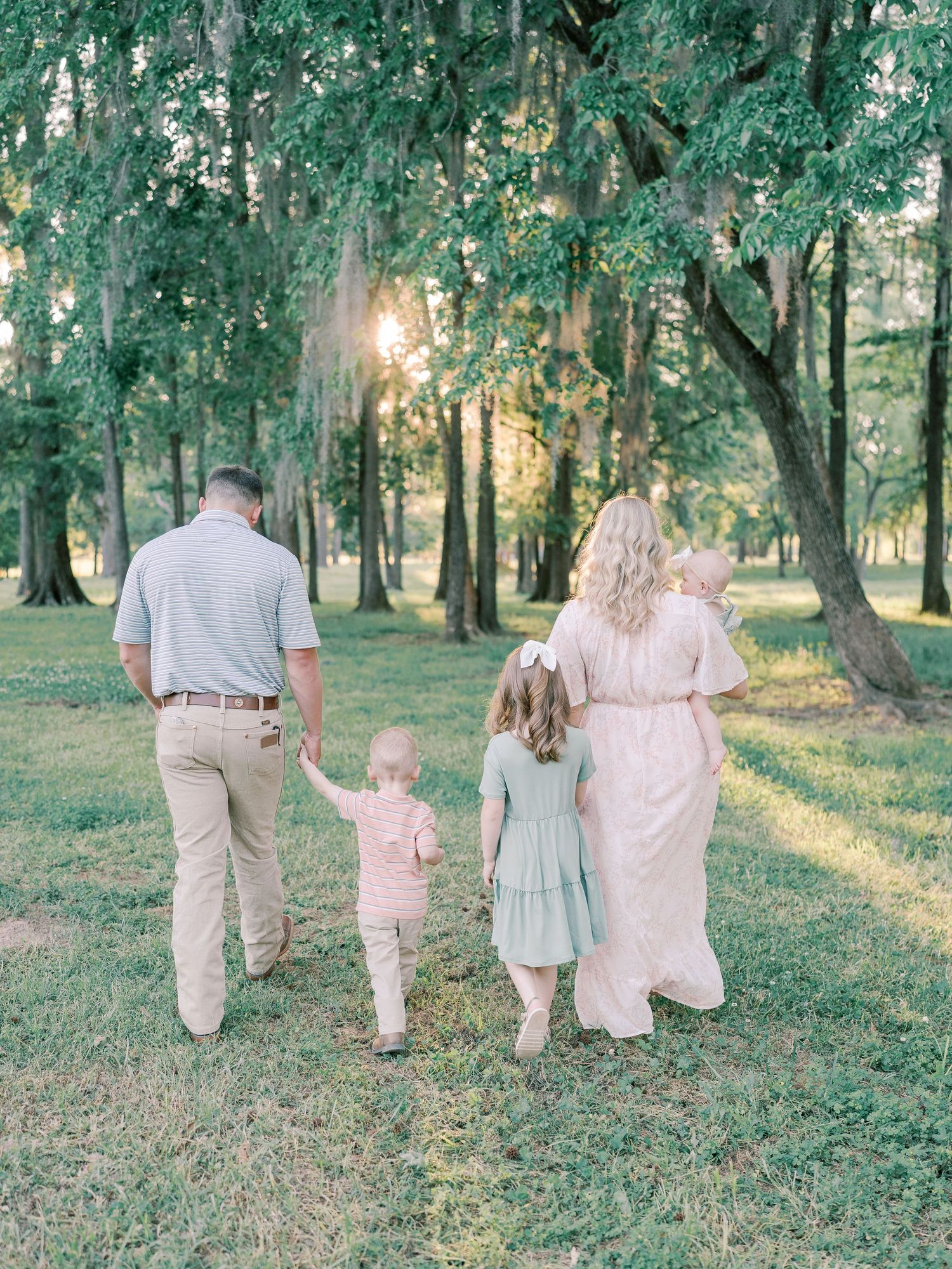 A group walks away from camera on a wooded trail during sunset.