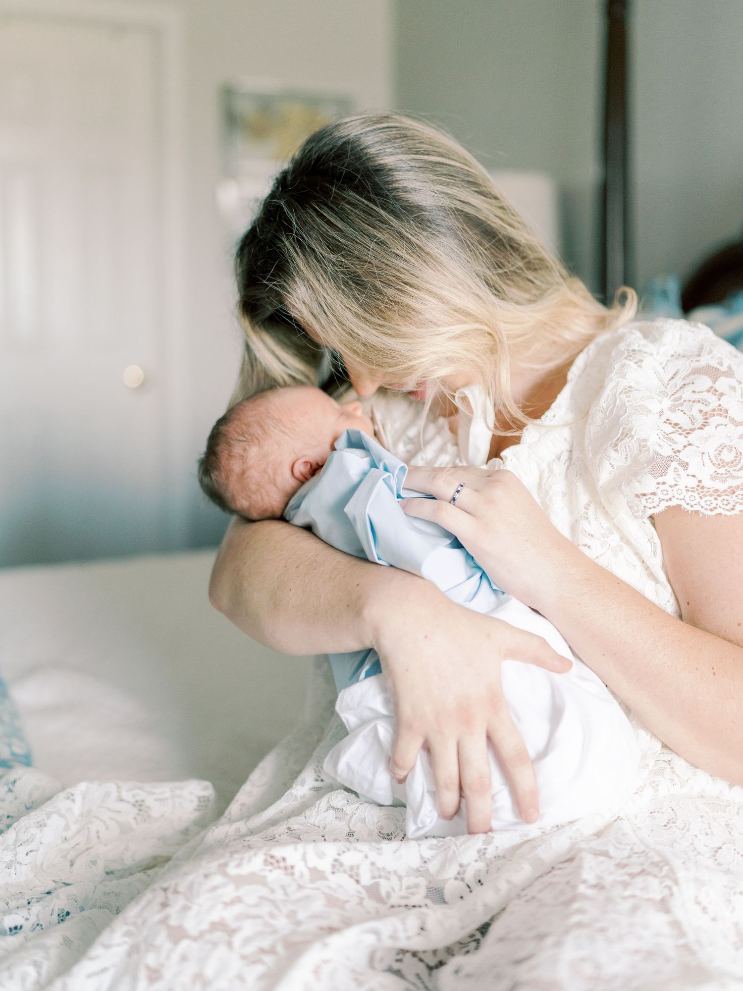 Tender moment between mother and baby on floral patterned bedding.