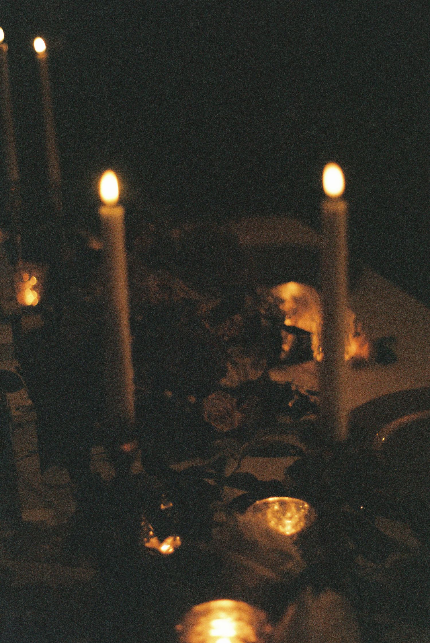 Romantic candlelit table setting with glowing flames in the darkness.