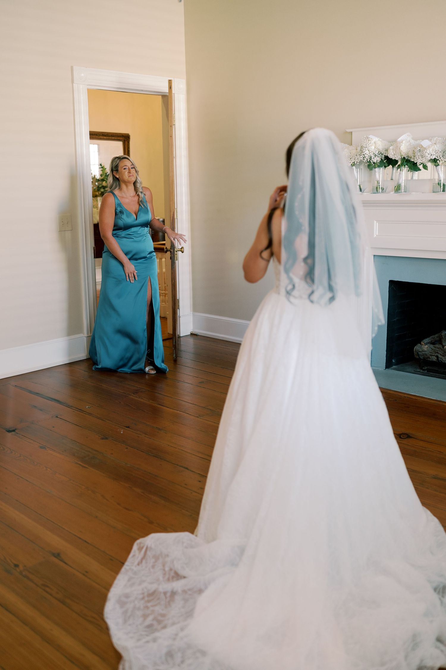 Sweet moment shared between wedding party members in a bright room with hardwood floors.