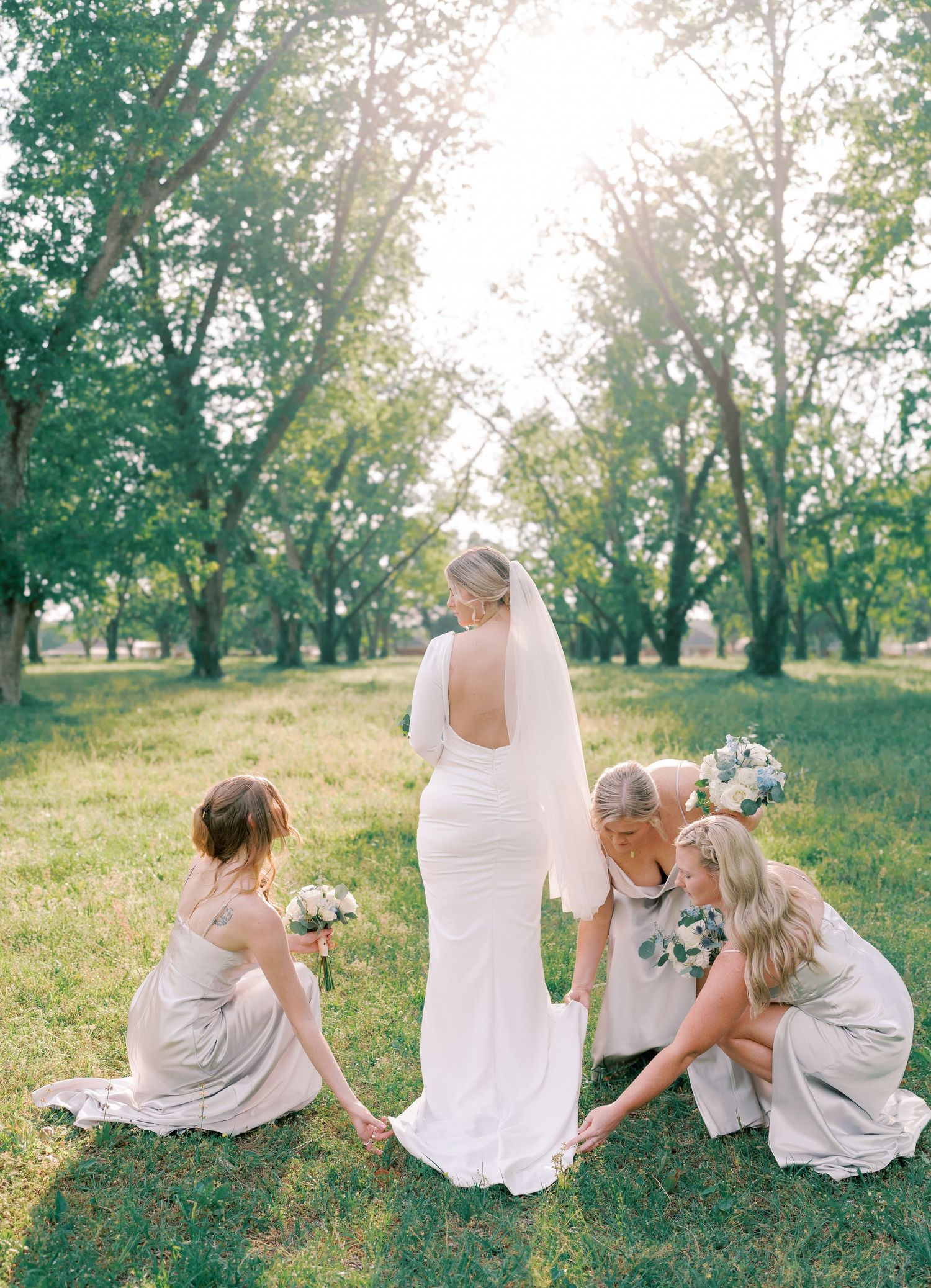 Family group sits together on grassy hillside in white summer outfits.