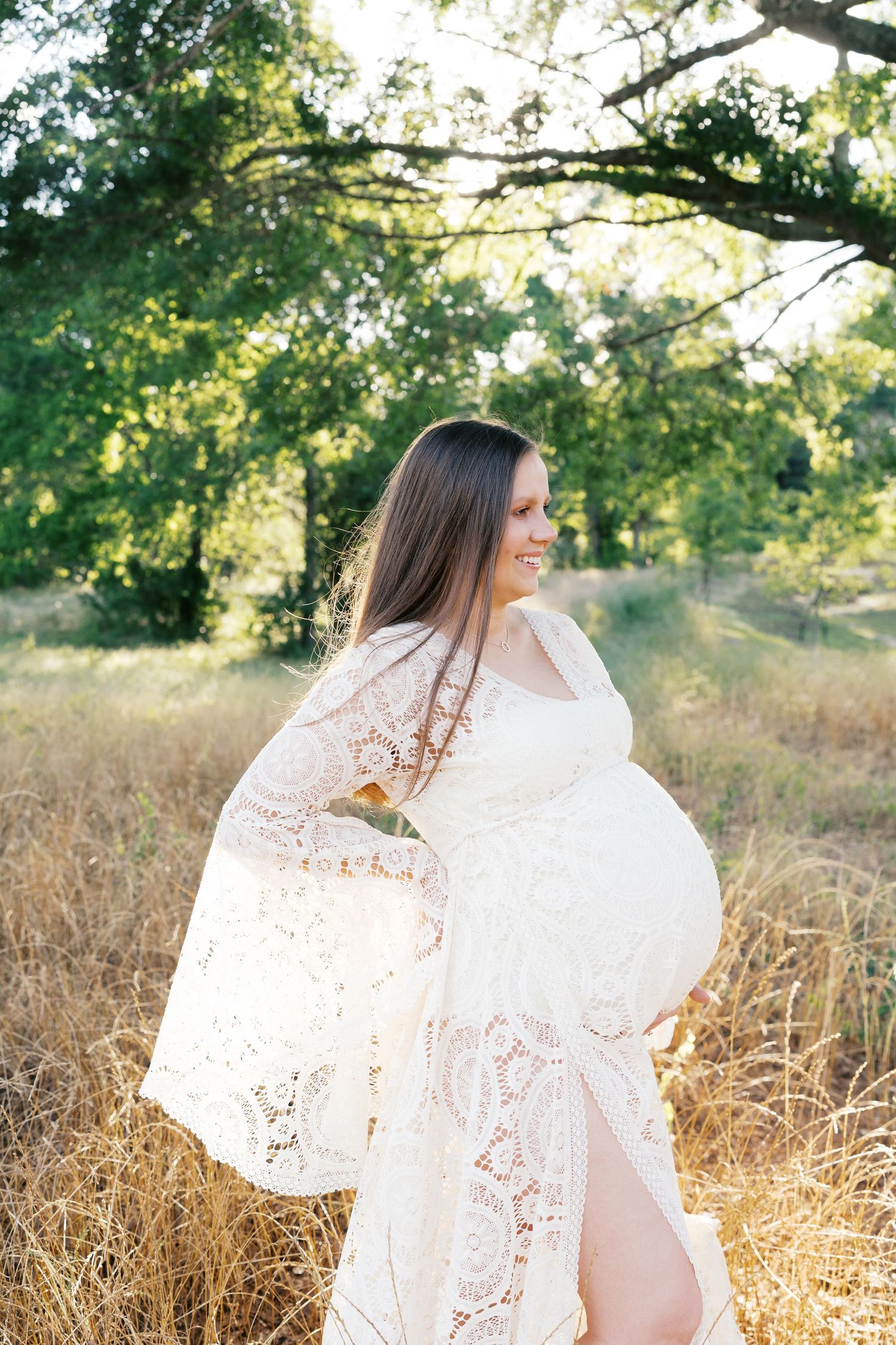 Elegant white lace dress twirls dramatically in sun-drenched field.