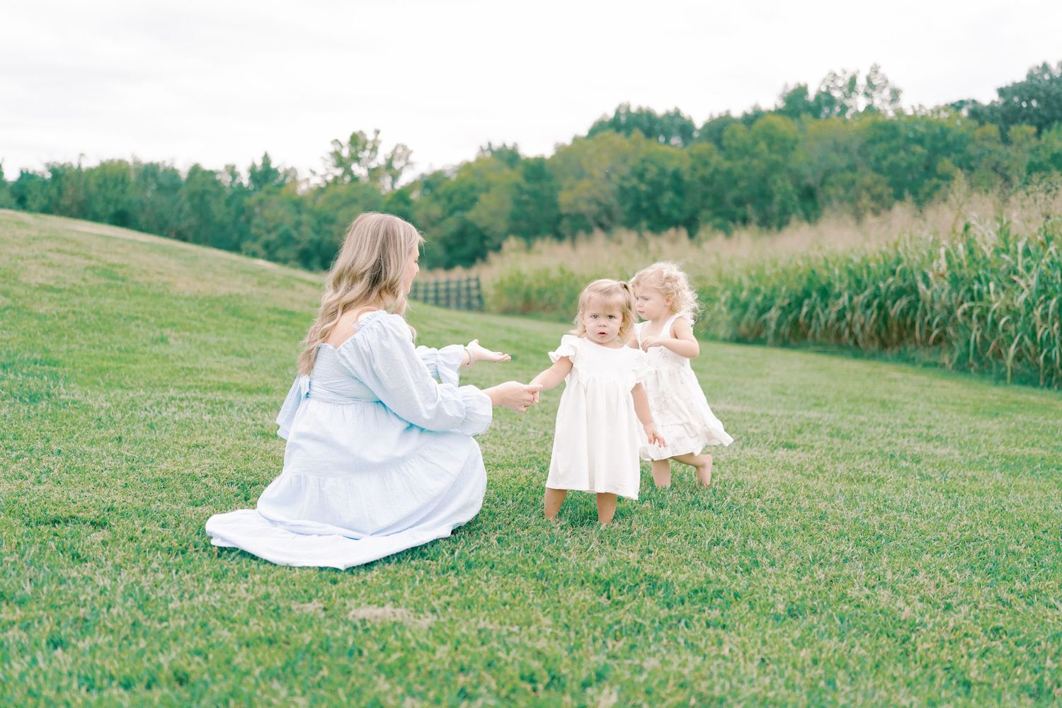 Candid family portraits taken in a serene grassy field with trees in the background.