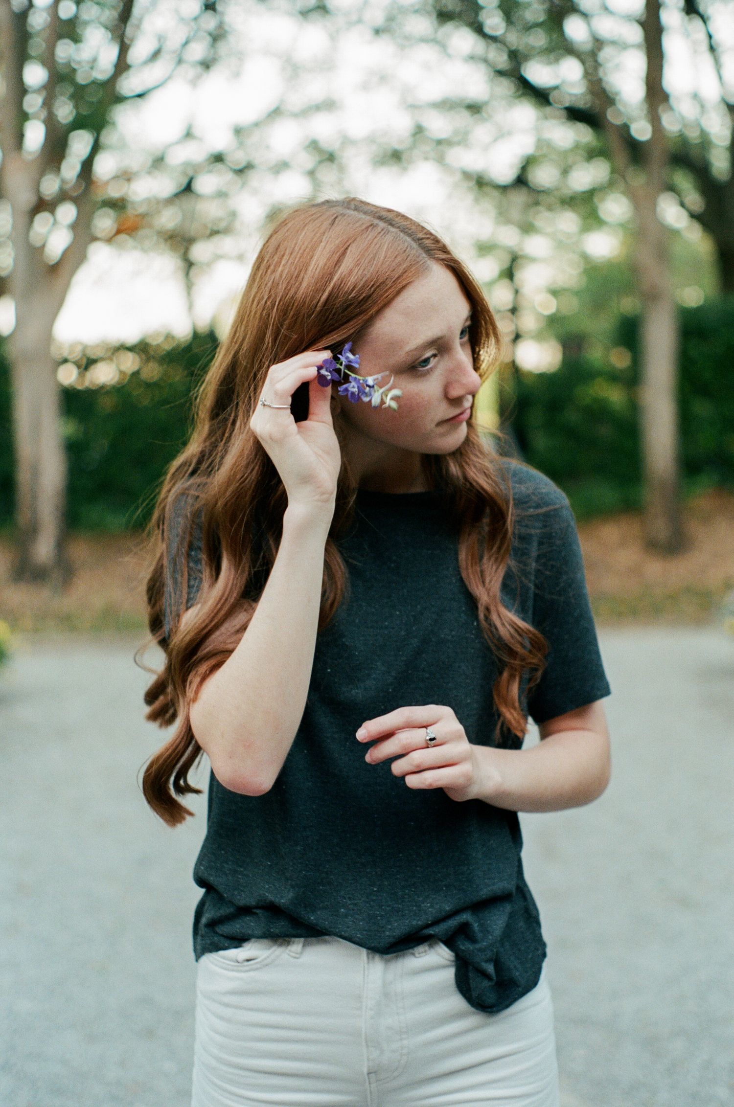 Person in dark shirt adjusting hair clip outdoors.