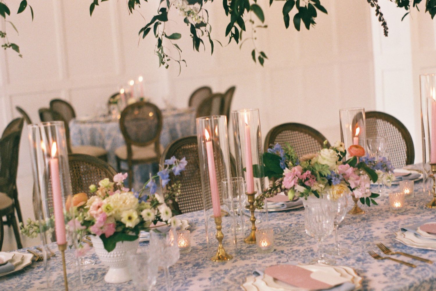 Elegant table setting with pink flowers and tall candles for a formal dining event.