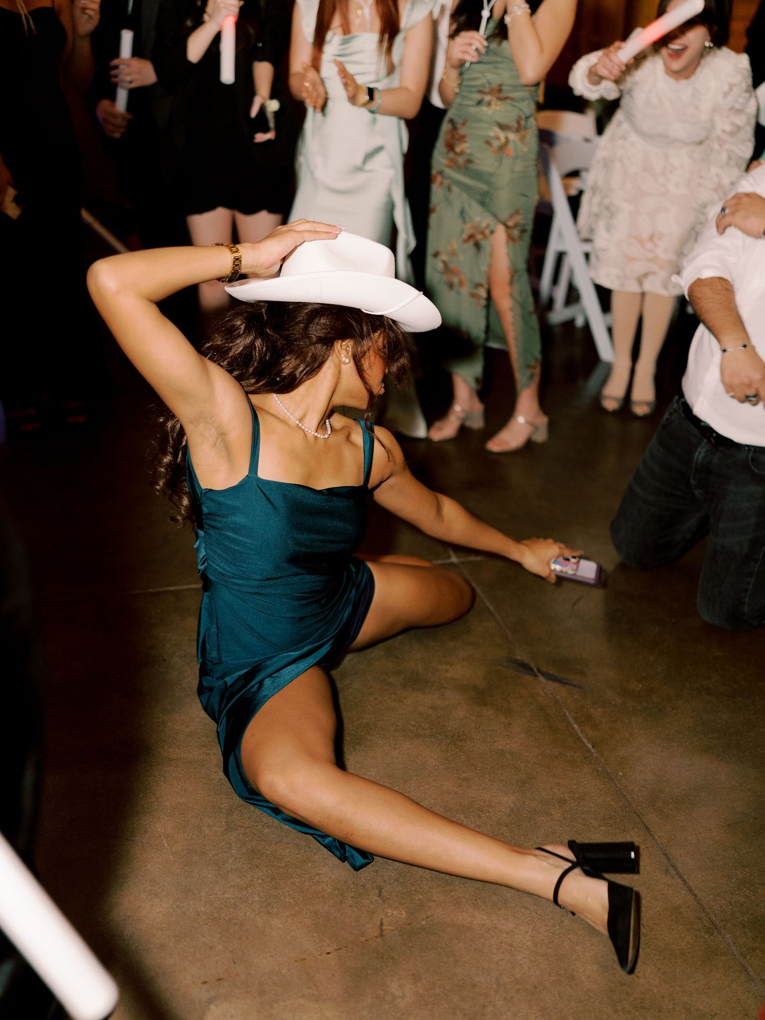 Dancer in teal dress performing dramatic splits move on dance floor.