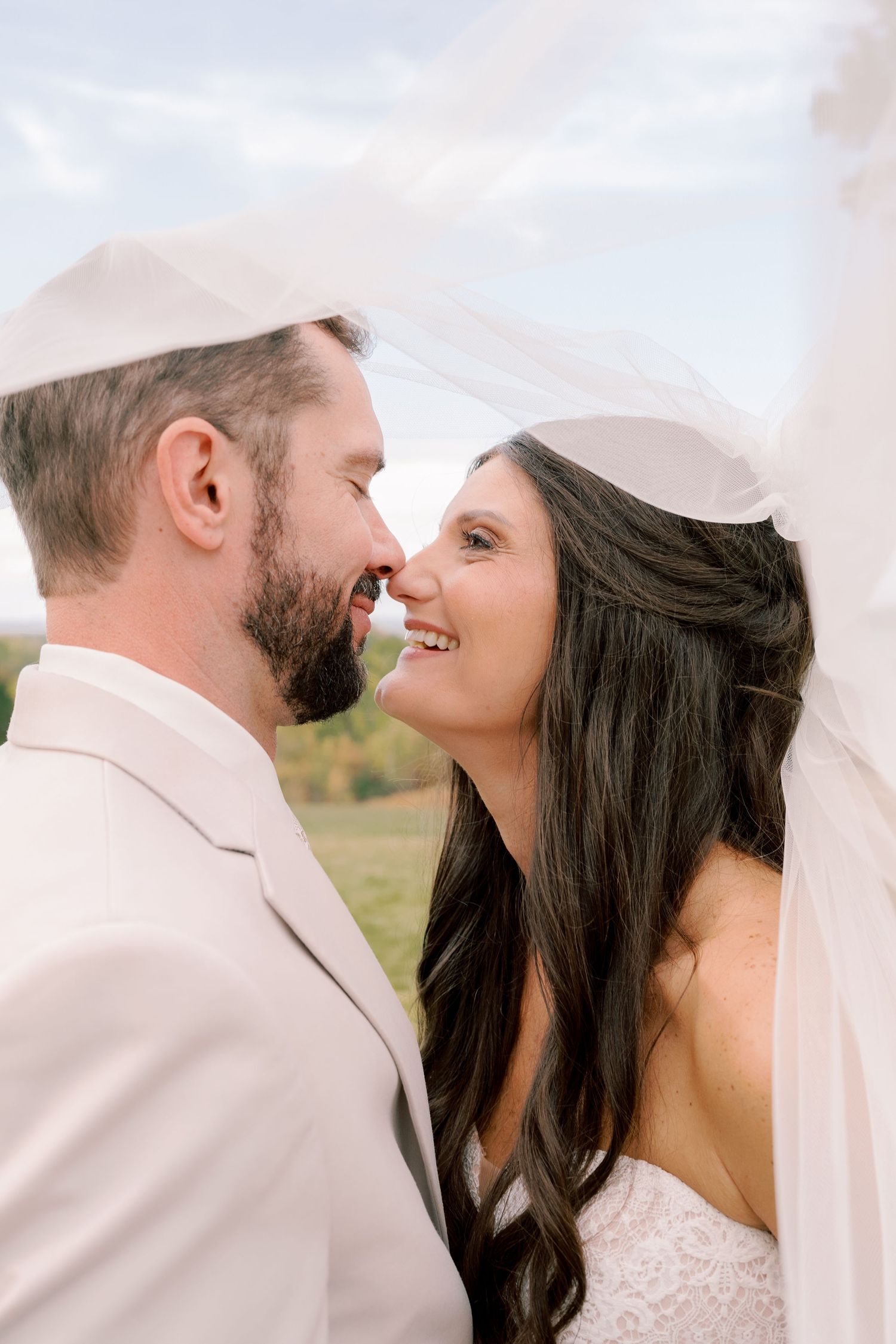 Intimate wedding portrait showing a tender moment between the couple under a flowing veil.