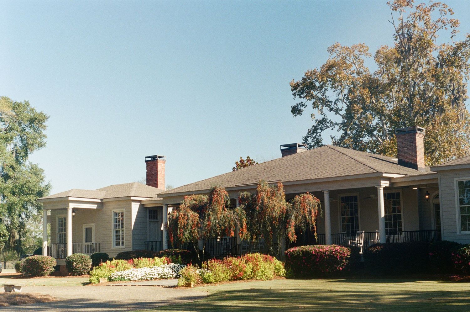 Exterior view of ranch-style house with landscaped yard in autumn.