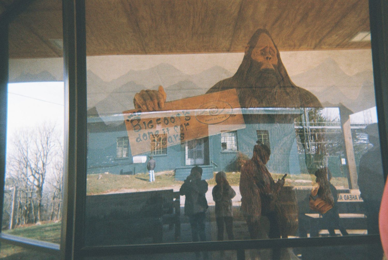 Silhouettes of people viewing an exhibit through a large window.
