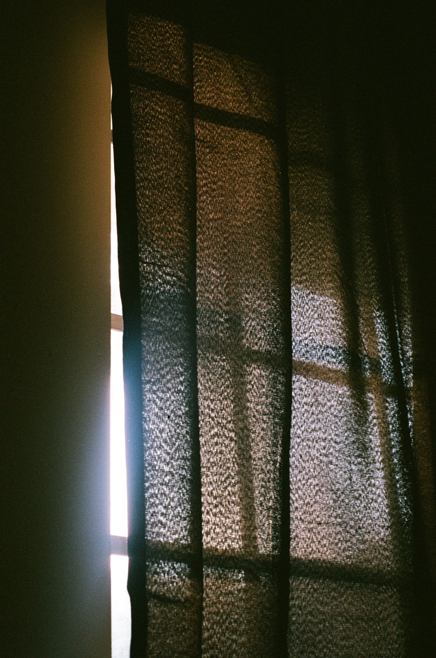 Sunlight filtering through textured curtains creates a rippled pattern effect.