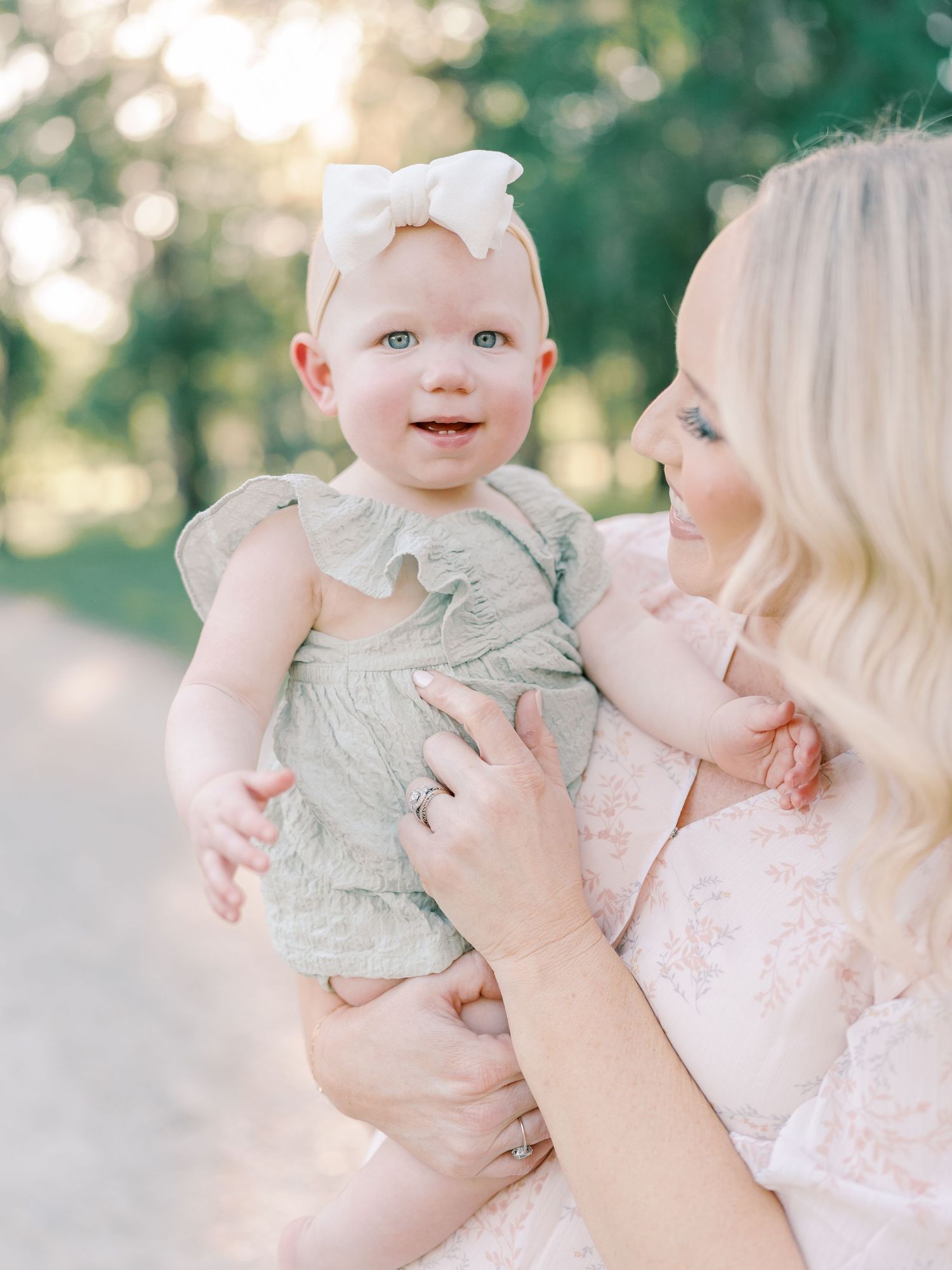 Sweet candid shots of a baby in grey clothing being held against a natural outdoor background.