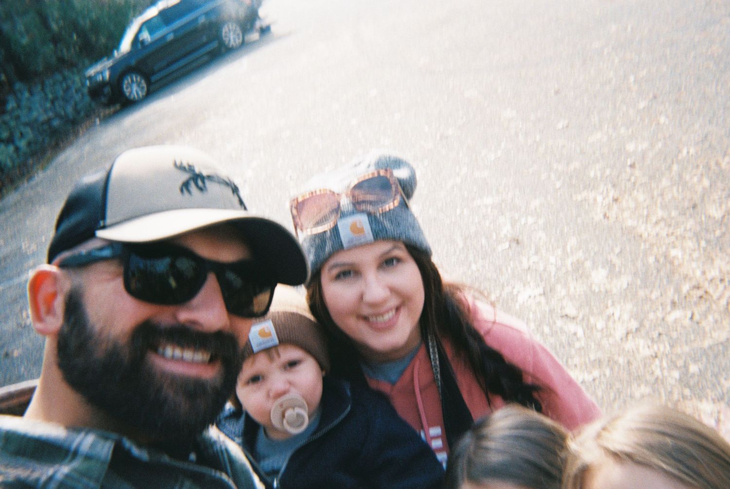 Family taking a casual outdoor selfie together on a sunny day.