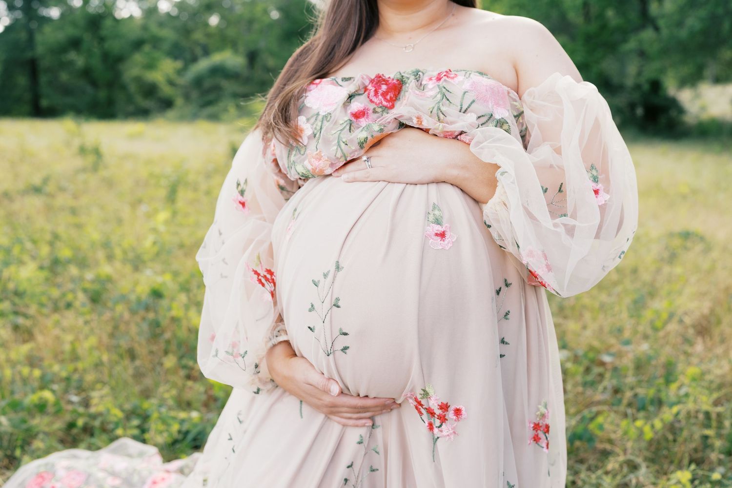 Close-up maternity photos showing details of pink floral dress in natural outdoor setting.