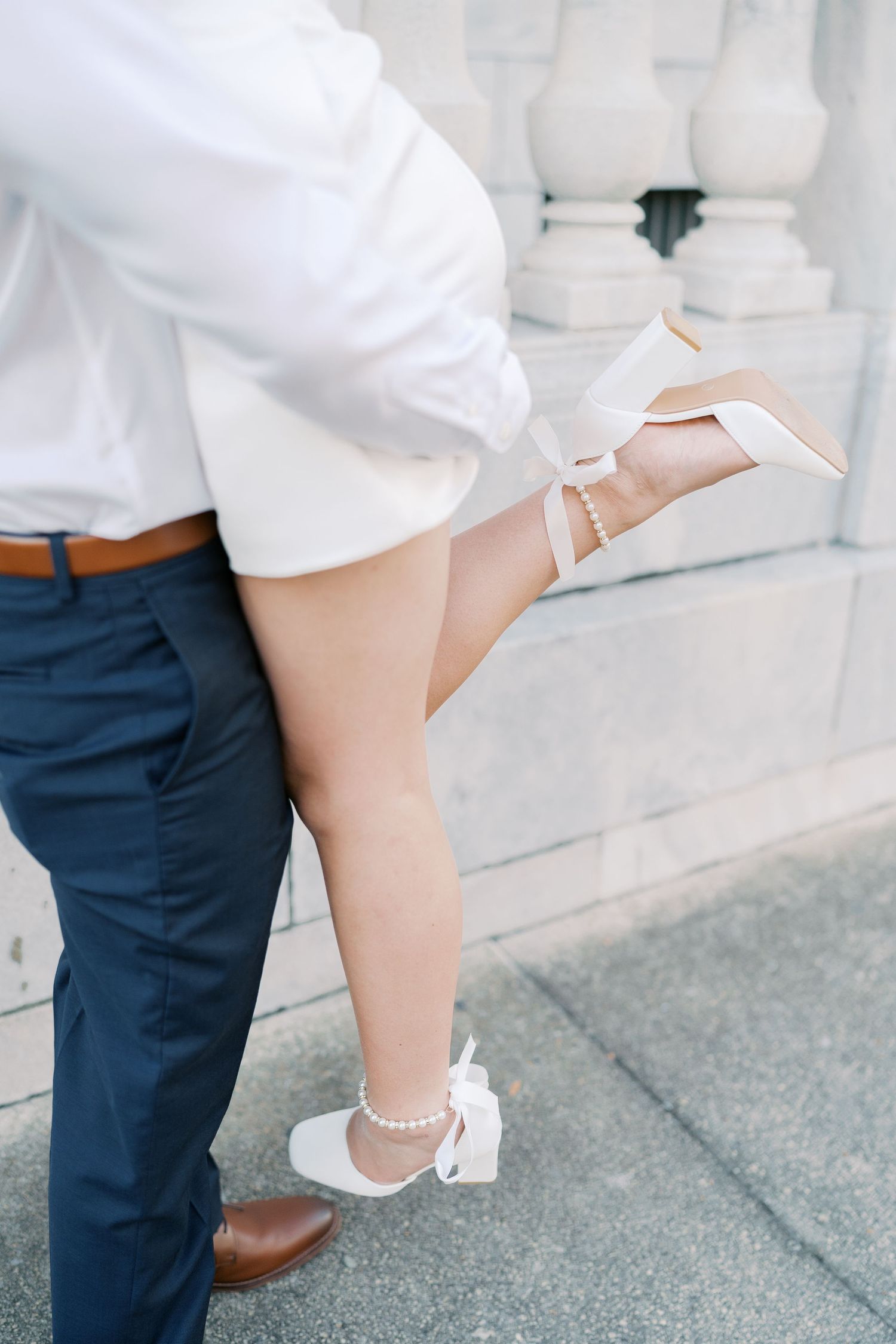 Close-up of elegant footwear and formal attire during romantic pose on stone steps.