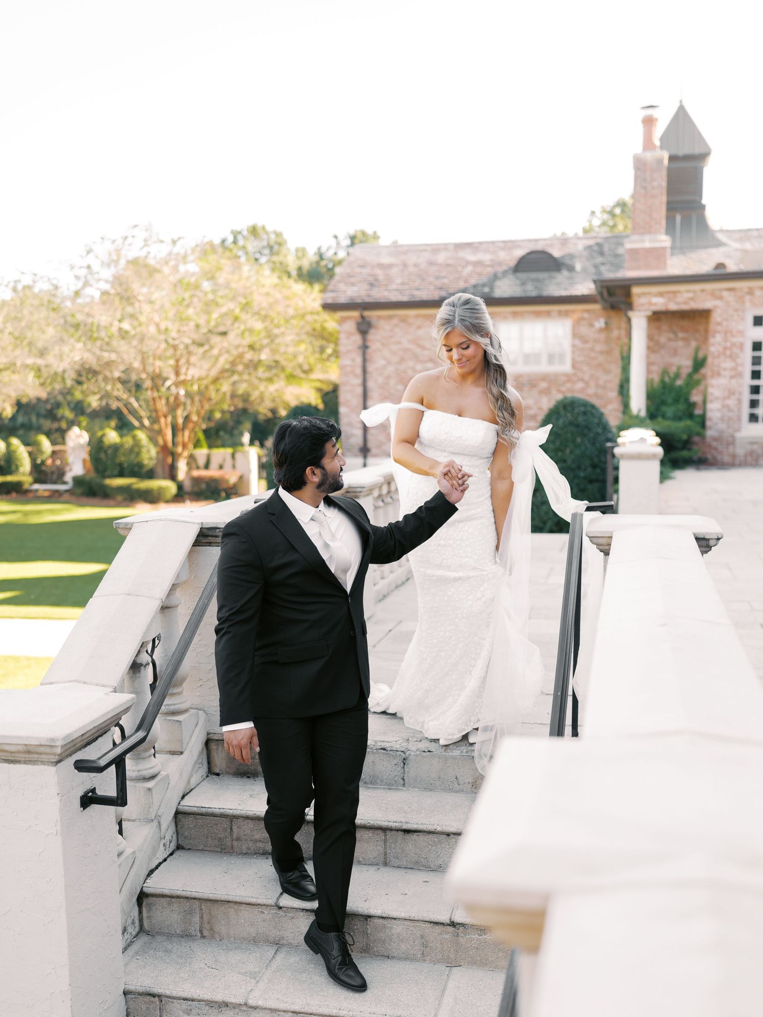 Wedding couple shares tender moments on white stone steps of elegant venue.