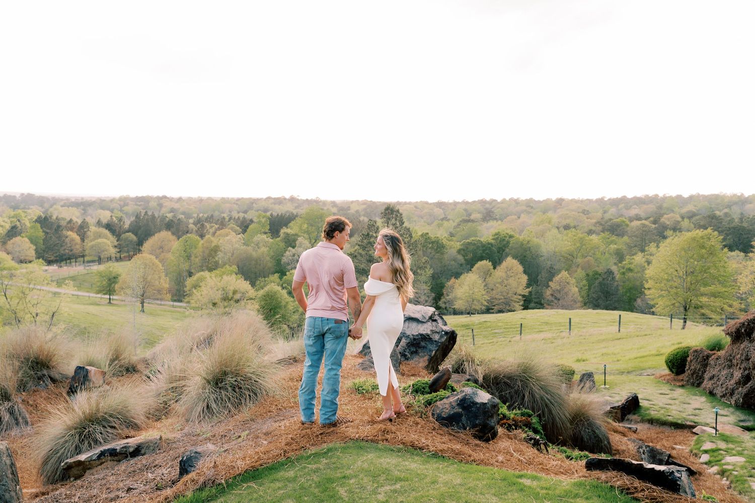 Couple celebrates on scenic hilltop overlooking rolling green countryside.