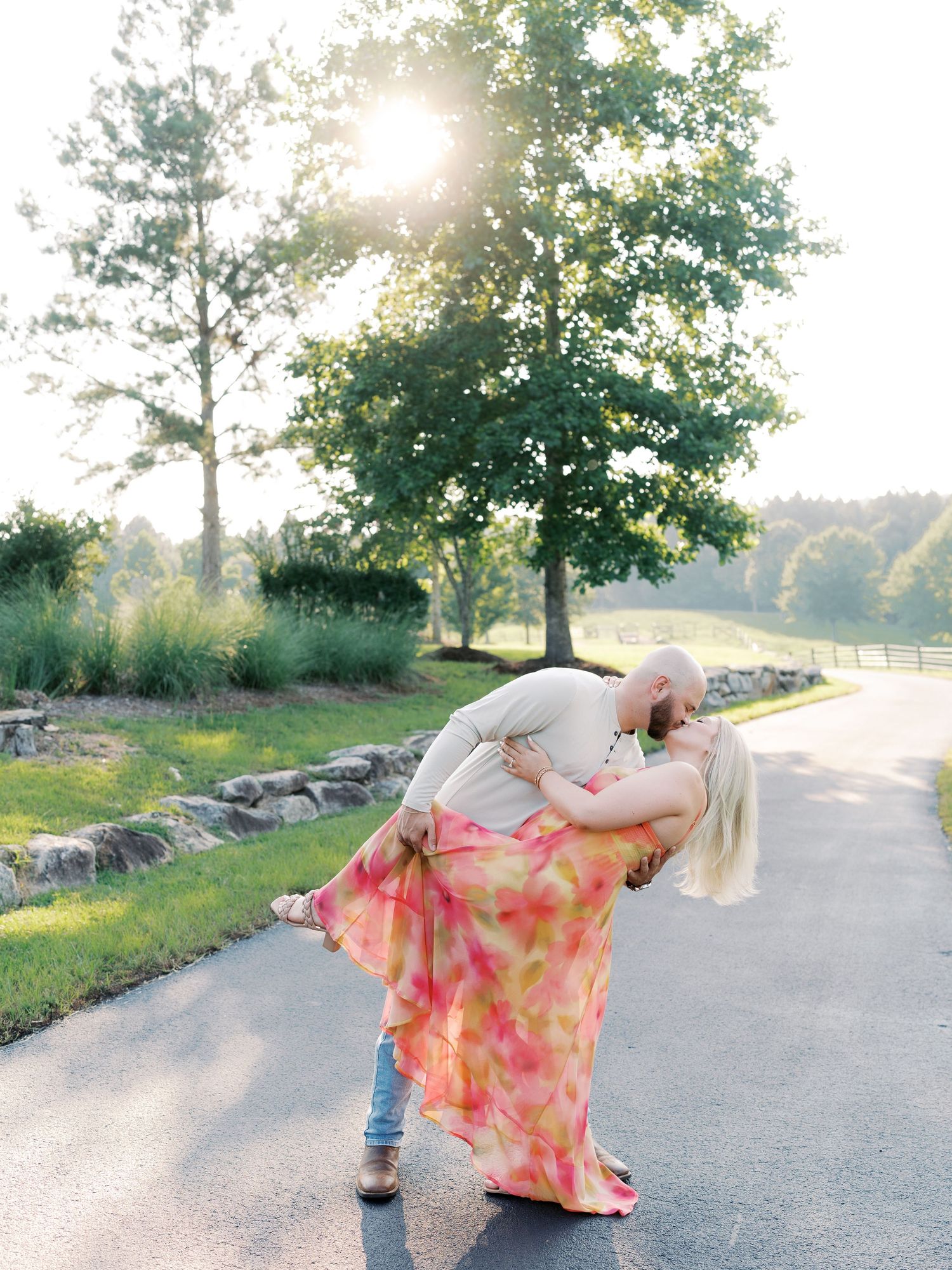 Playful dancing scene on sunlit path with trees and stone wall.