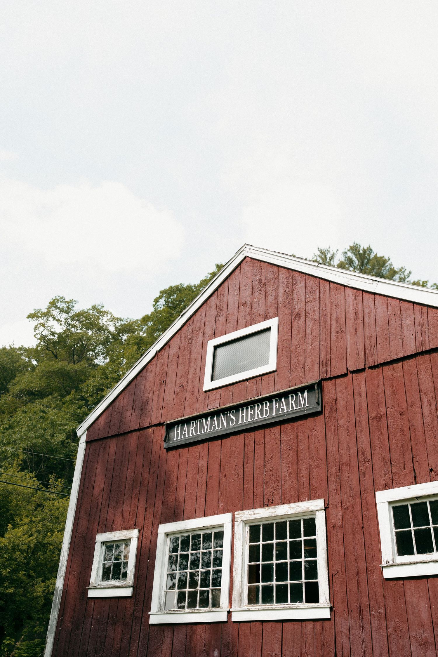 A classic red barn with white trim windows and 'Hardman's Department' sign on the exterior.