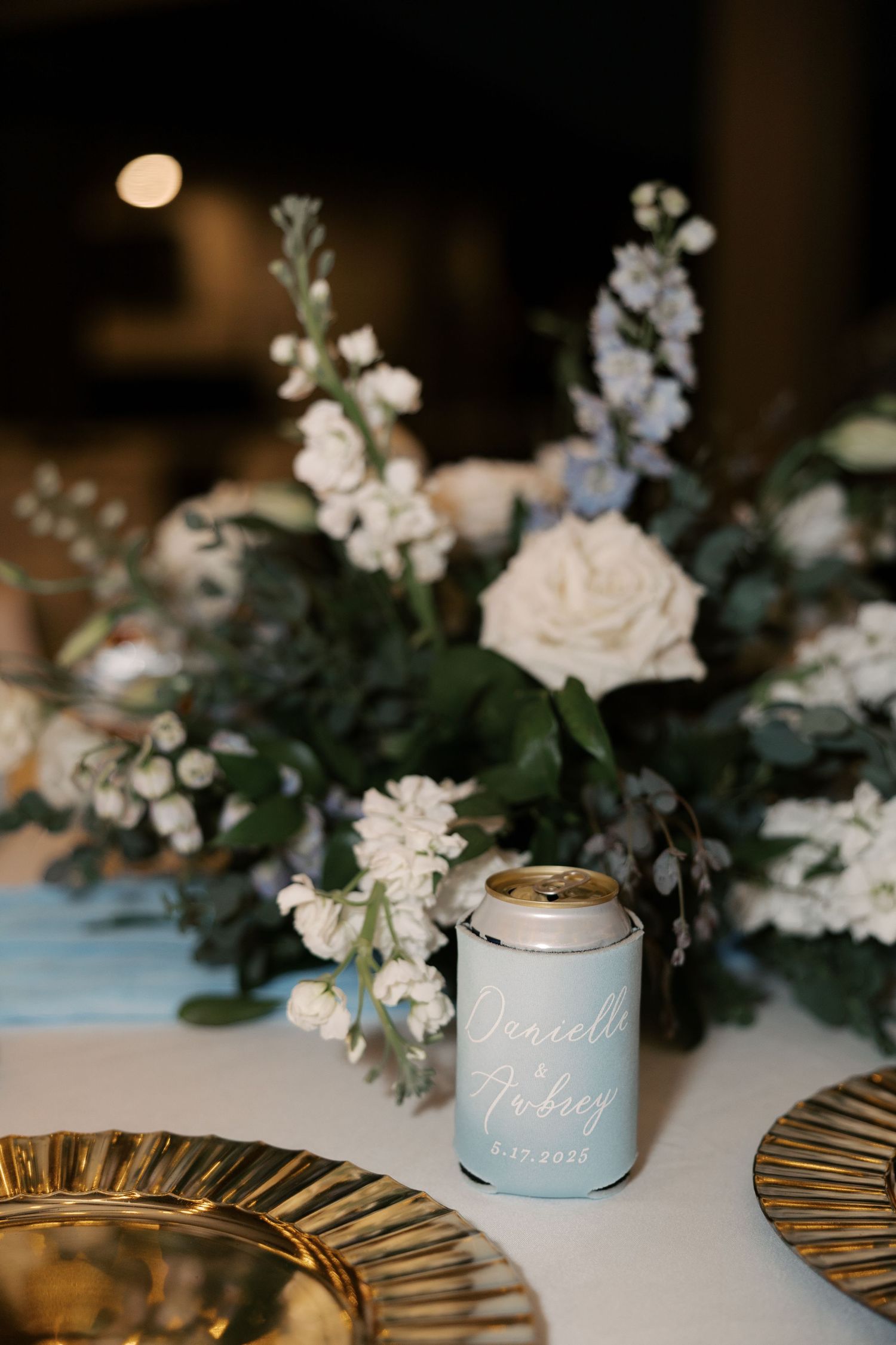 Wedding table decor with white floral arrangements and gold charger plates.