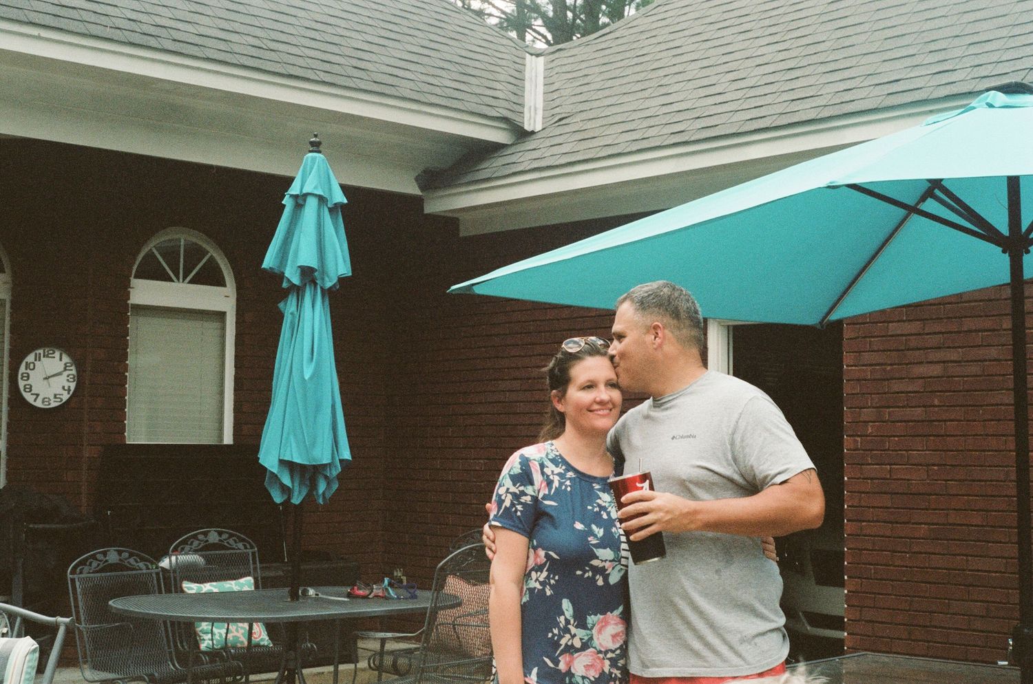 Casual gathering on a brick patio with turquoise umbrellas and outdoor seating.