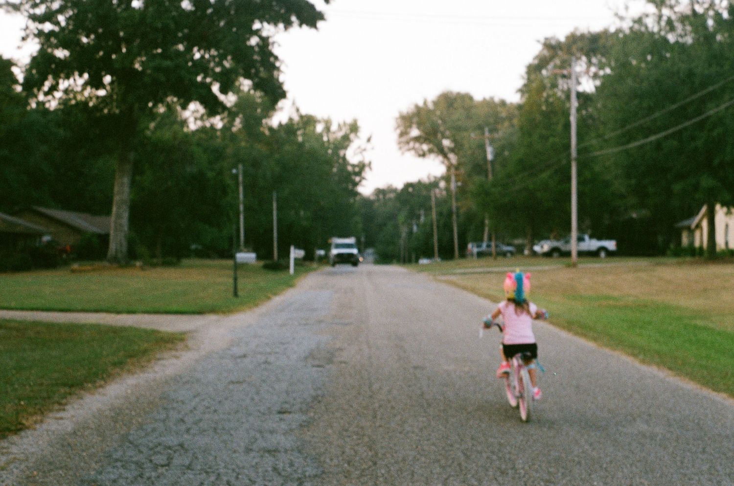 Long gravel path through a grassy park with trees lining the sides.