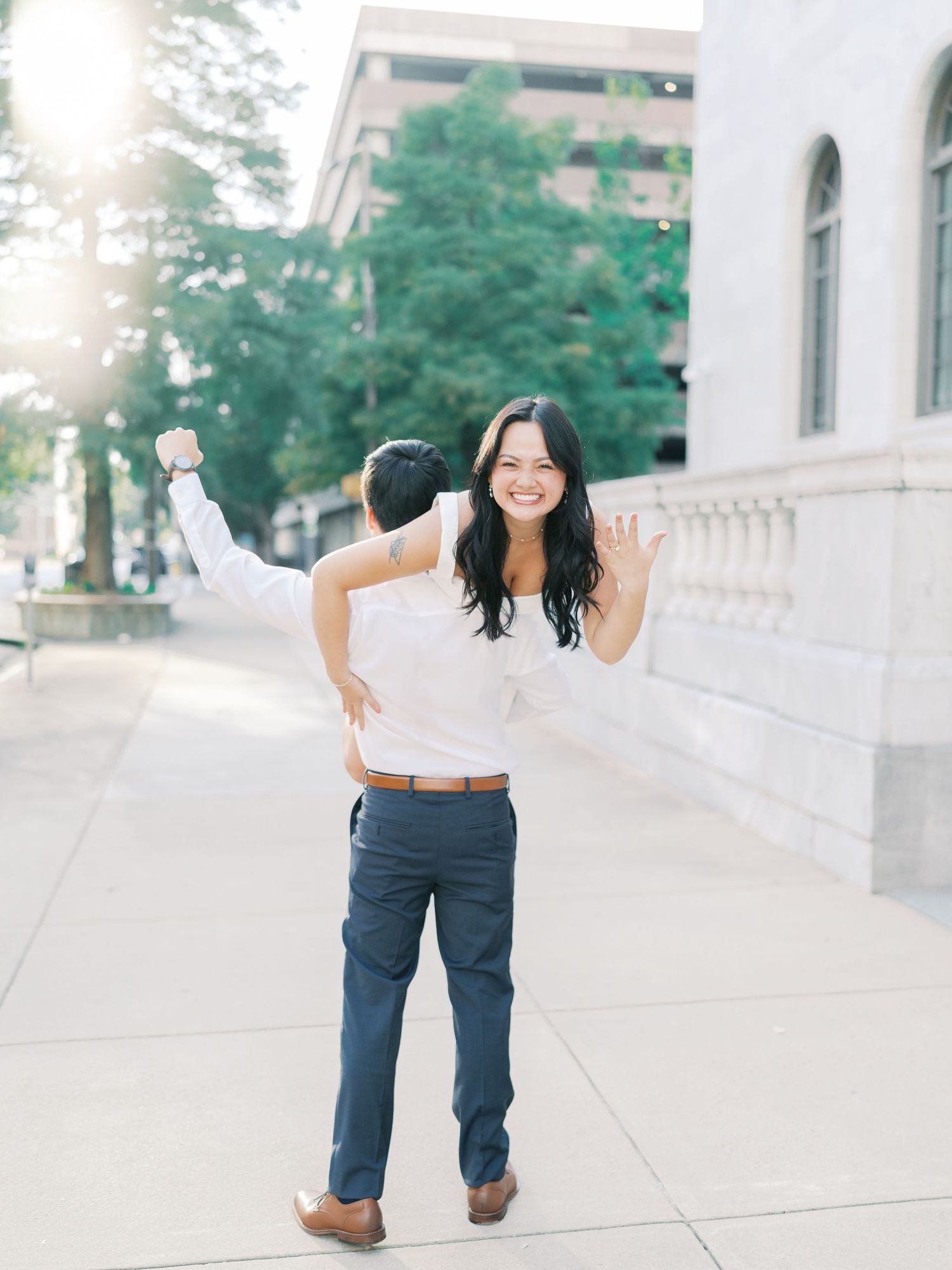 Energetic poses captured during an outdoor photoshoot along a white building exterior.