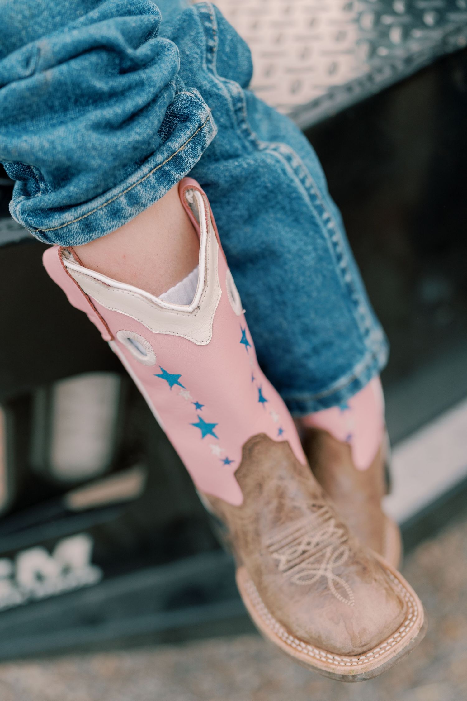 Pink and brown cowboy boot with blue star details worn with jeans.