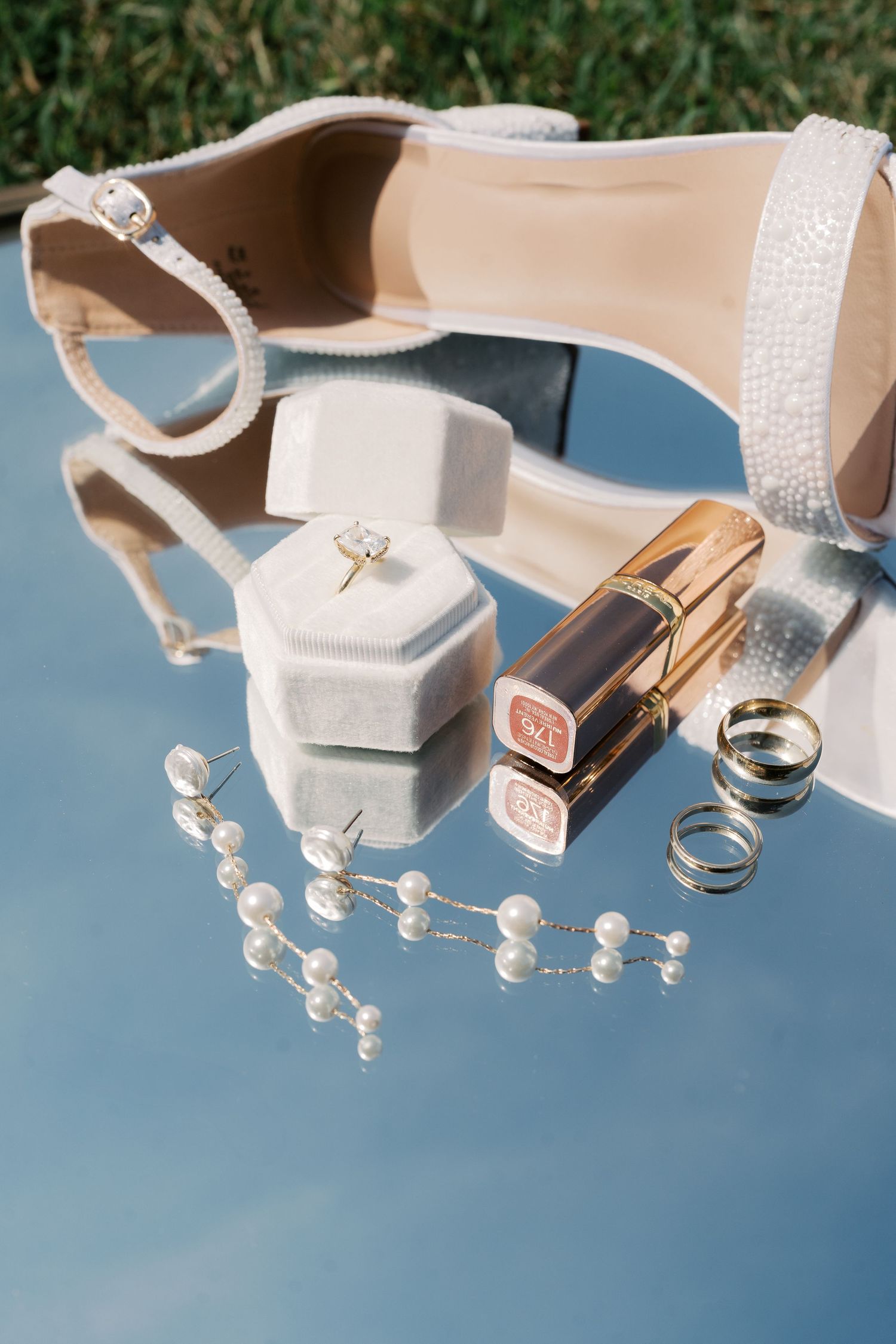 Wedding jewelry, rings and accessories arranged on light blue surface with delicate styling.