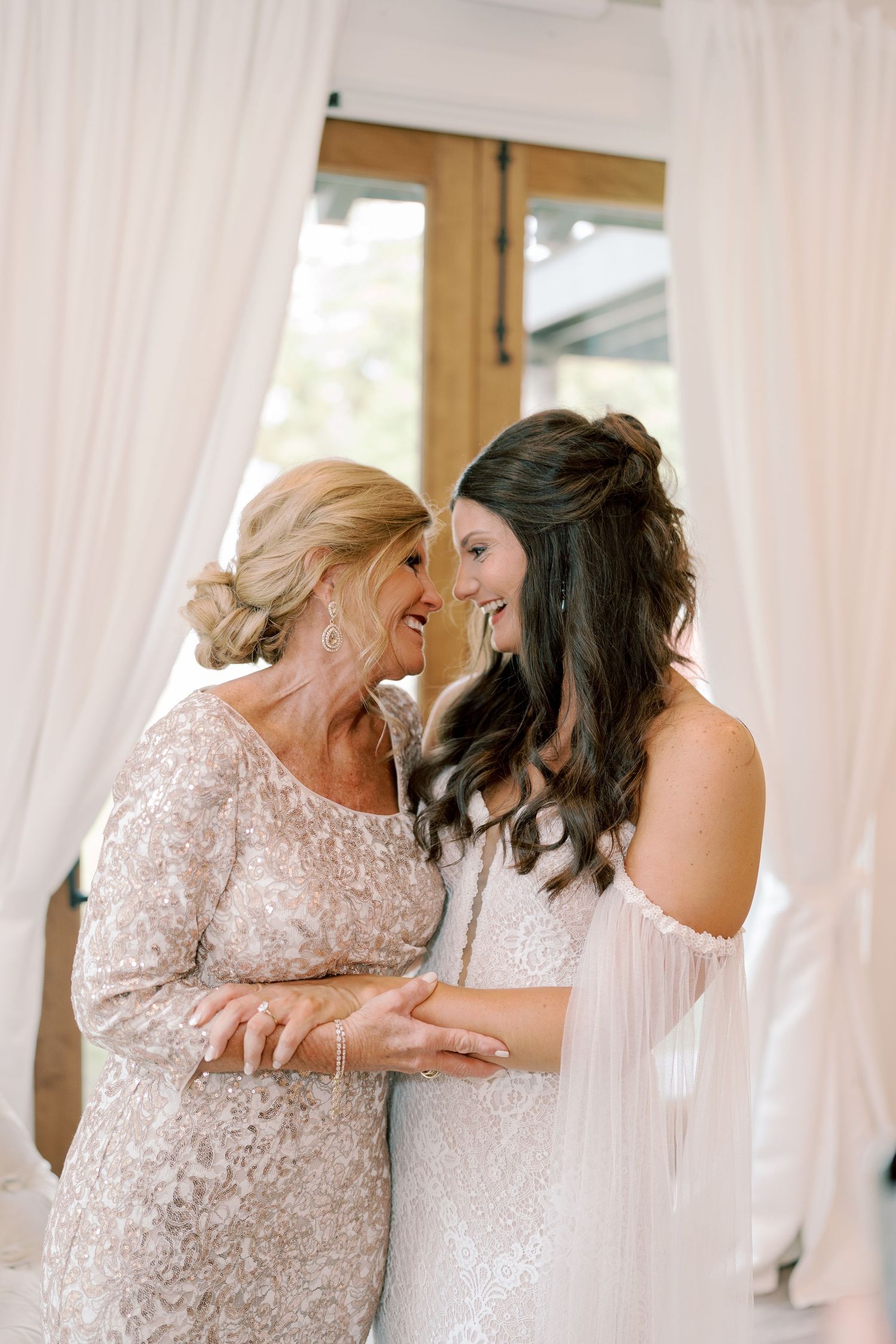 Emotional wedding party moment shared in a bright indoor venue with white curtains.