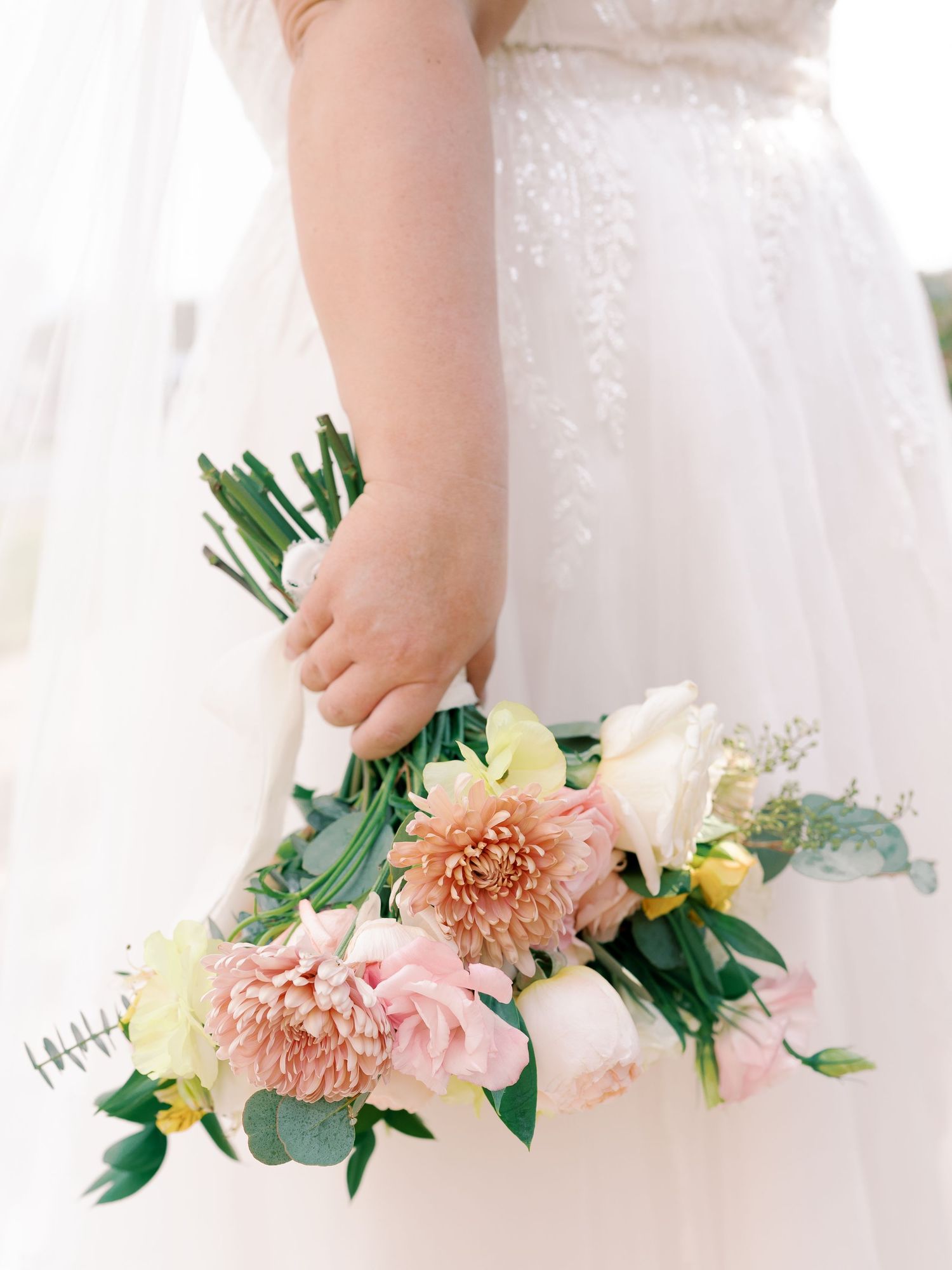 Close-up of a bridal bouquet featuring peach dahlias and mixed flowers.