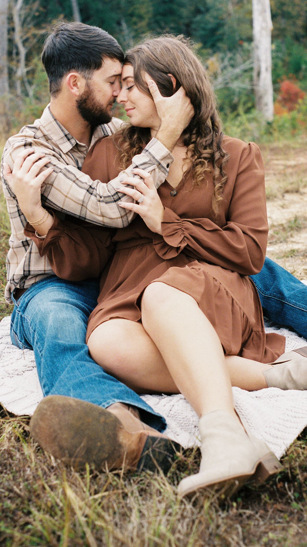 Intimate couple sharing a romantic moment on a blanket outdoors.