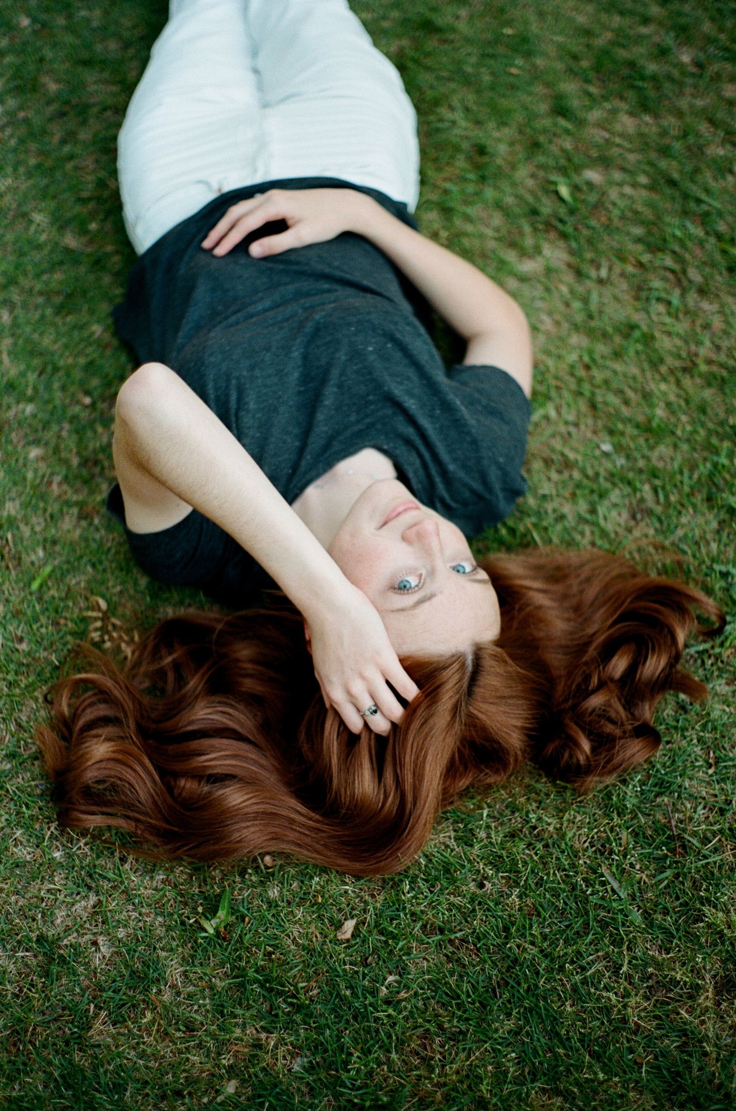 Artistic portrait lying on grass with flowing hair spread out.