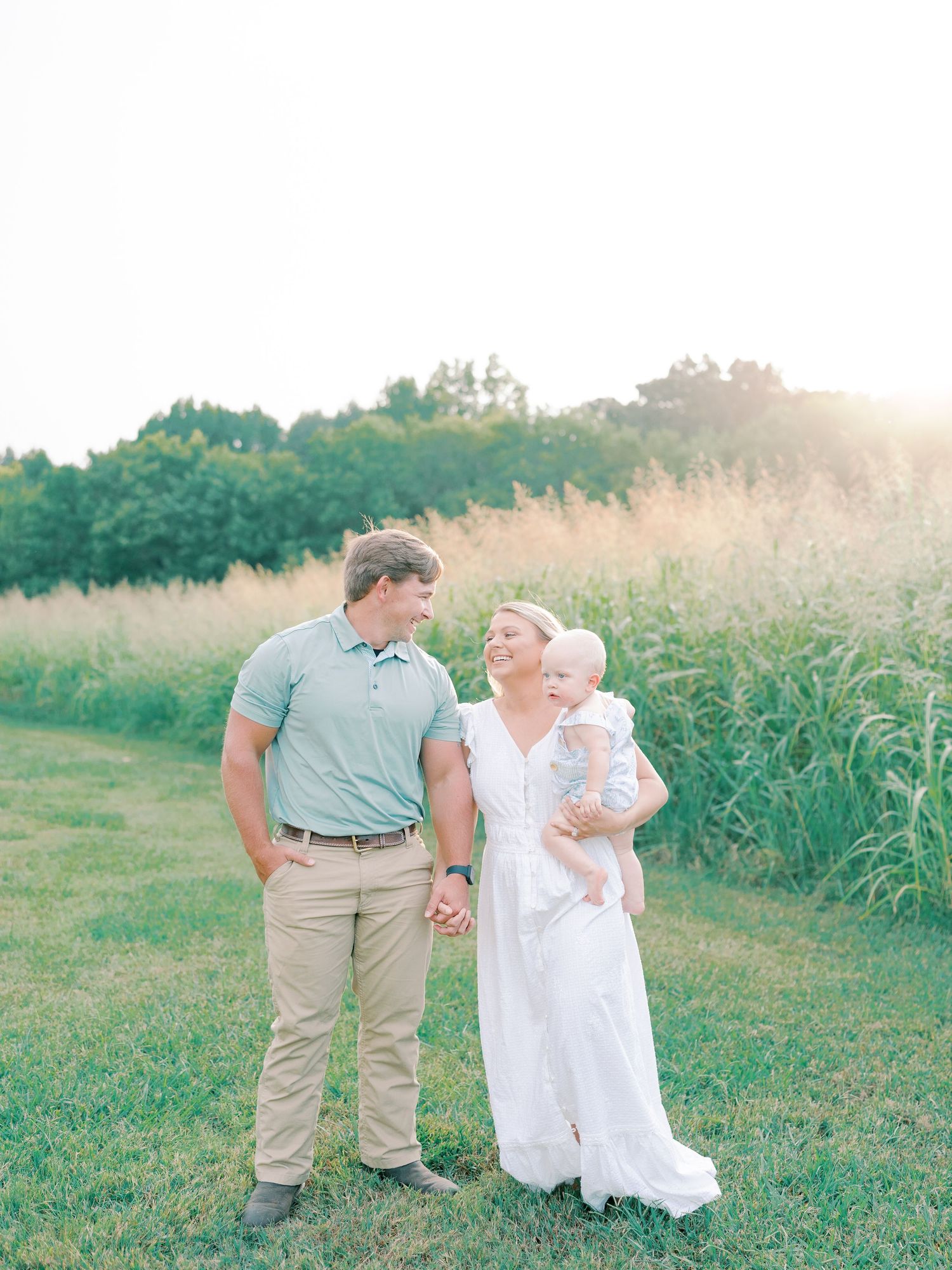 Family shares tender moments together in a sunlit field during golden hour.