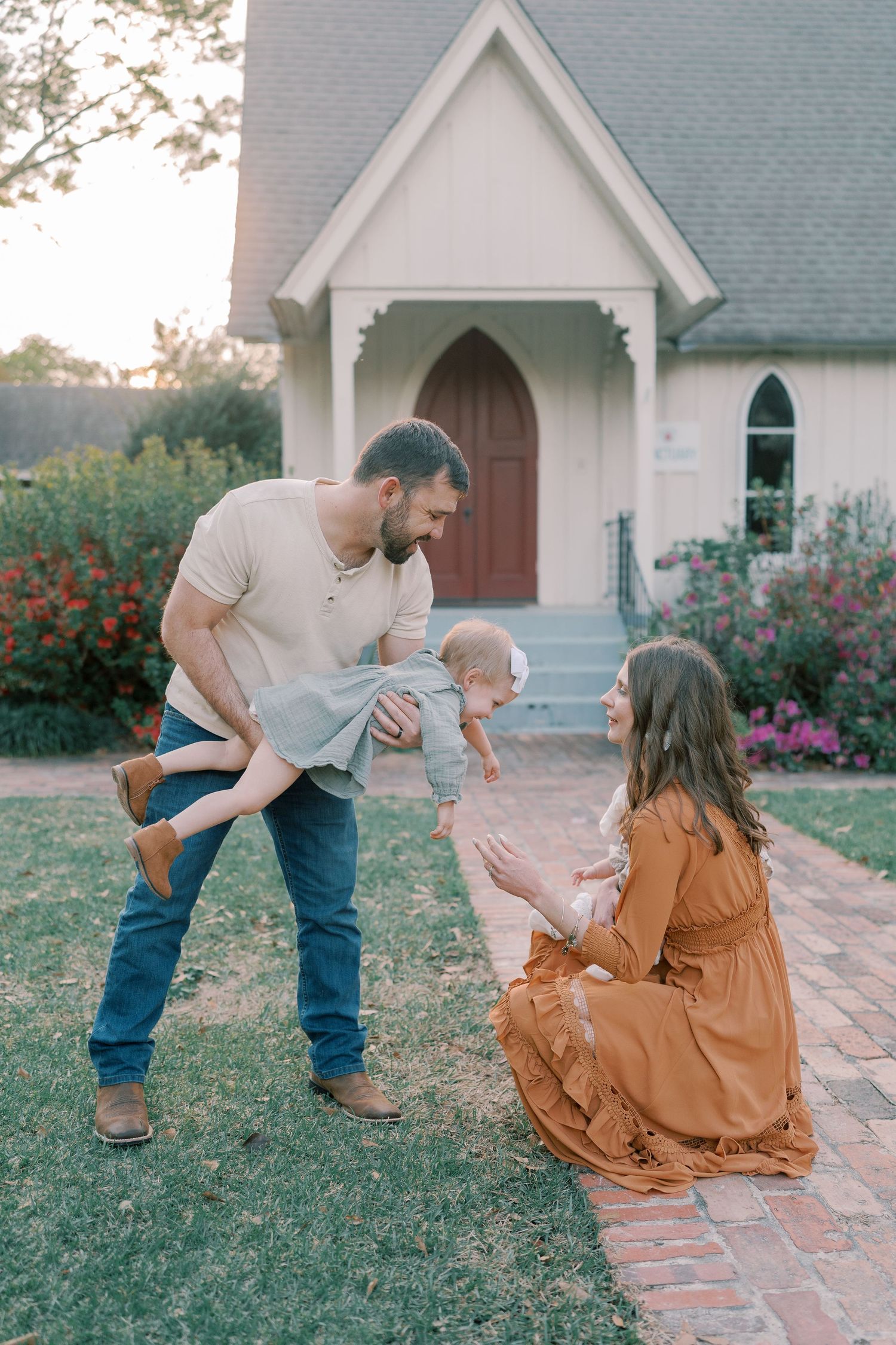 A family plays together on a brick pathway in front of a white church building.