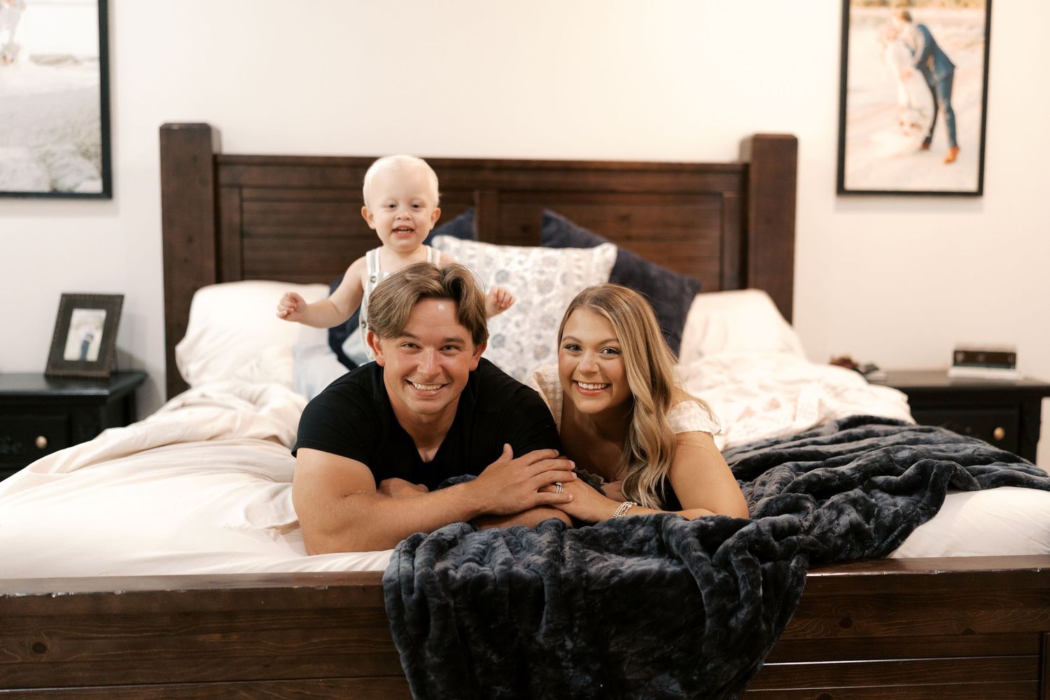 Sweet family moments shared on a bed with black blanket and wooden frame.