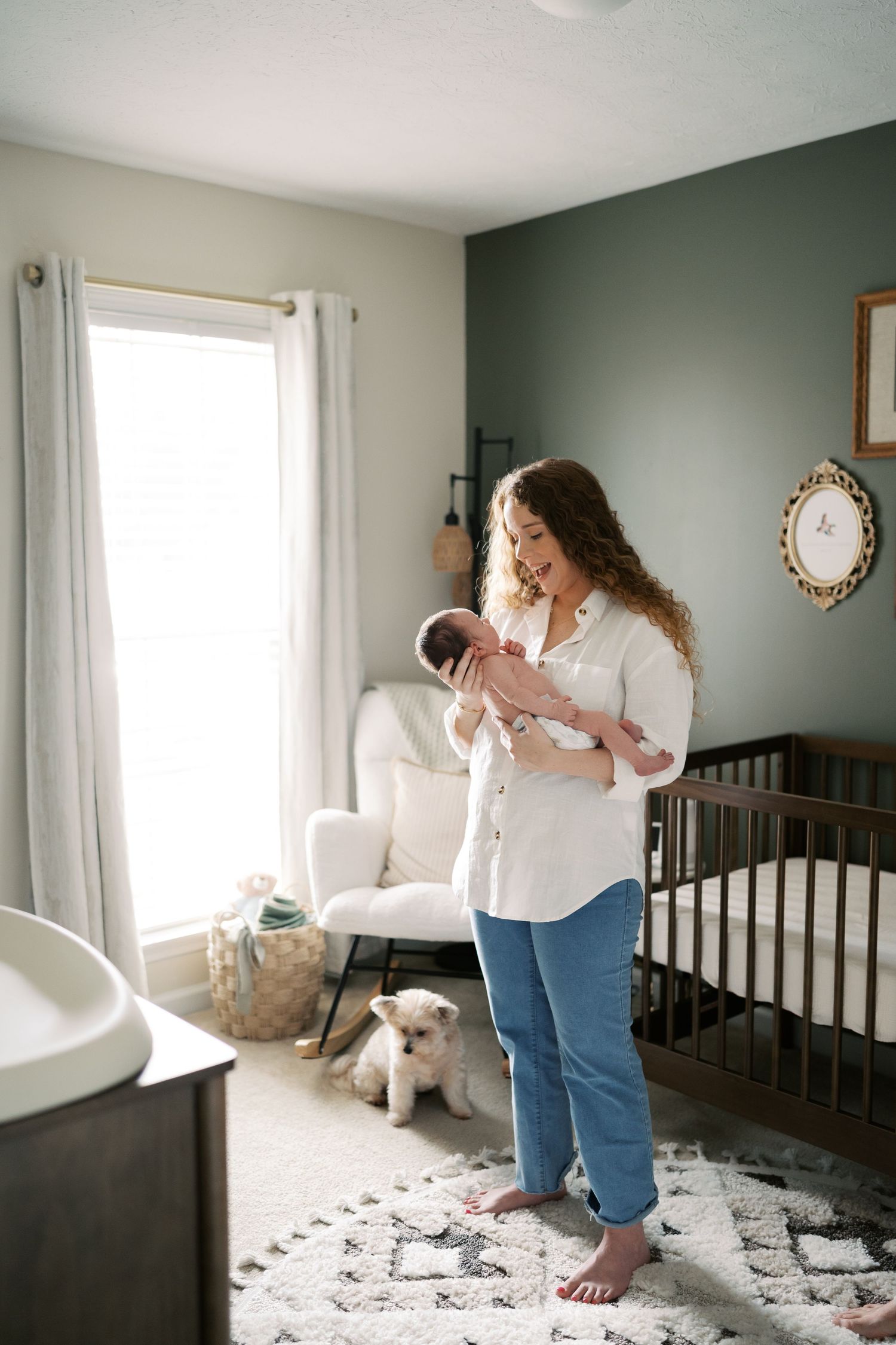 Nursery room with dark green walls, crib, and area rug showing intimate family moments.