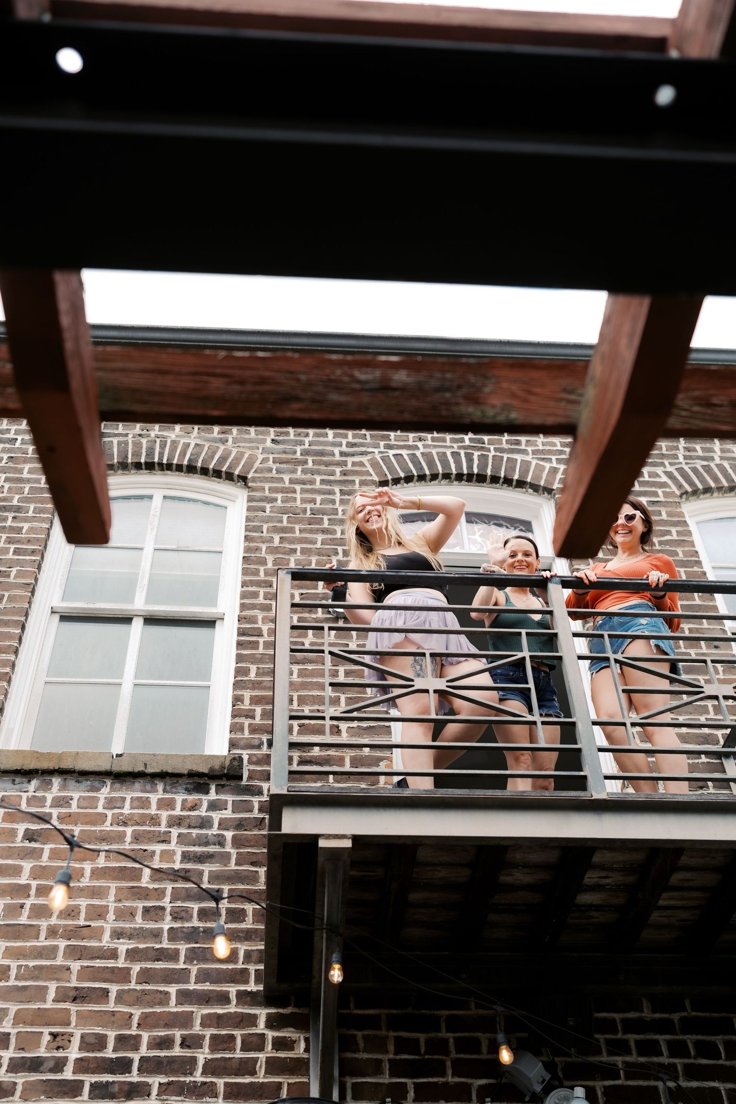 Silhouettes of people dancing on a rooftop against a brick building backdrop.