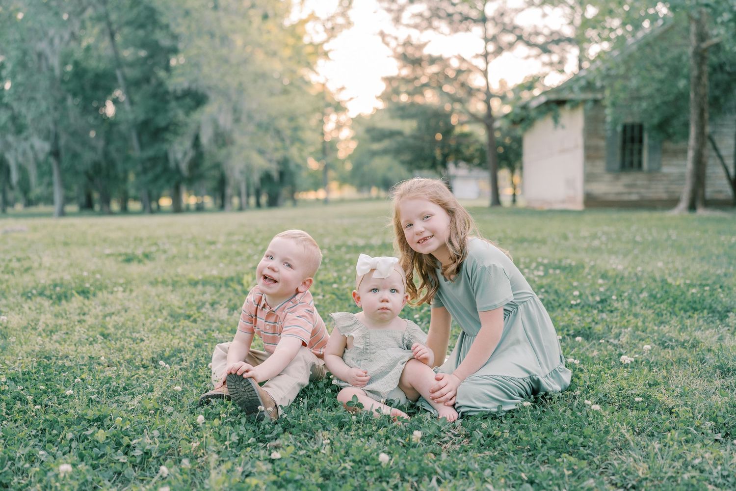 Family enjoys outdoor photoshoot in grassy field at sunset.