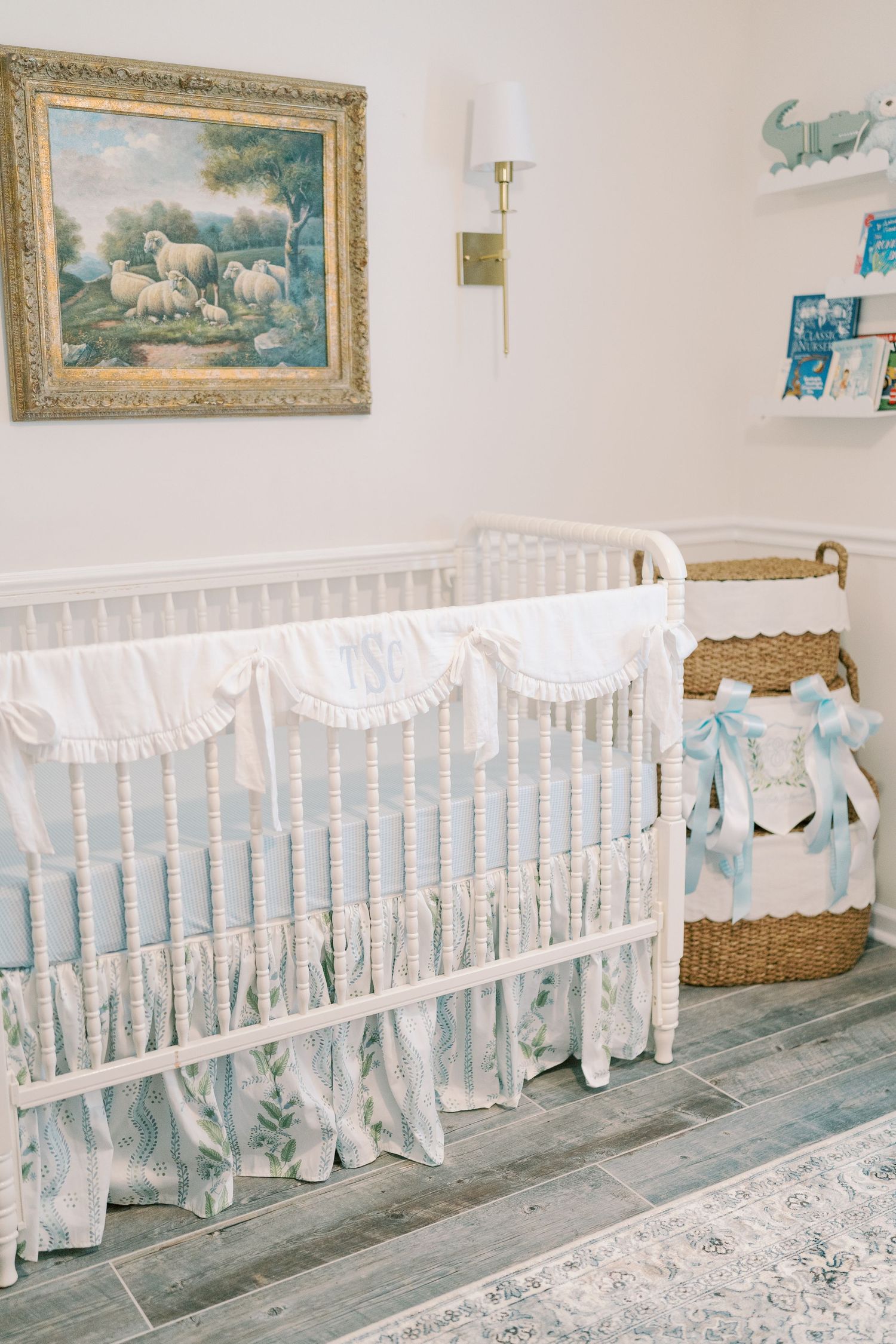 Elegant nursery room with white crib, framed artwork, and blue accents.